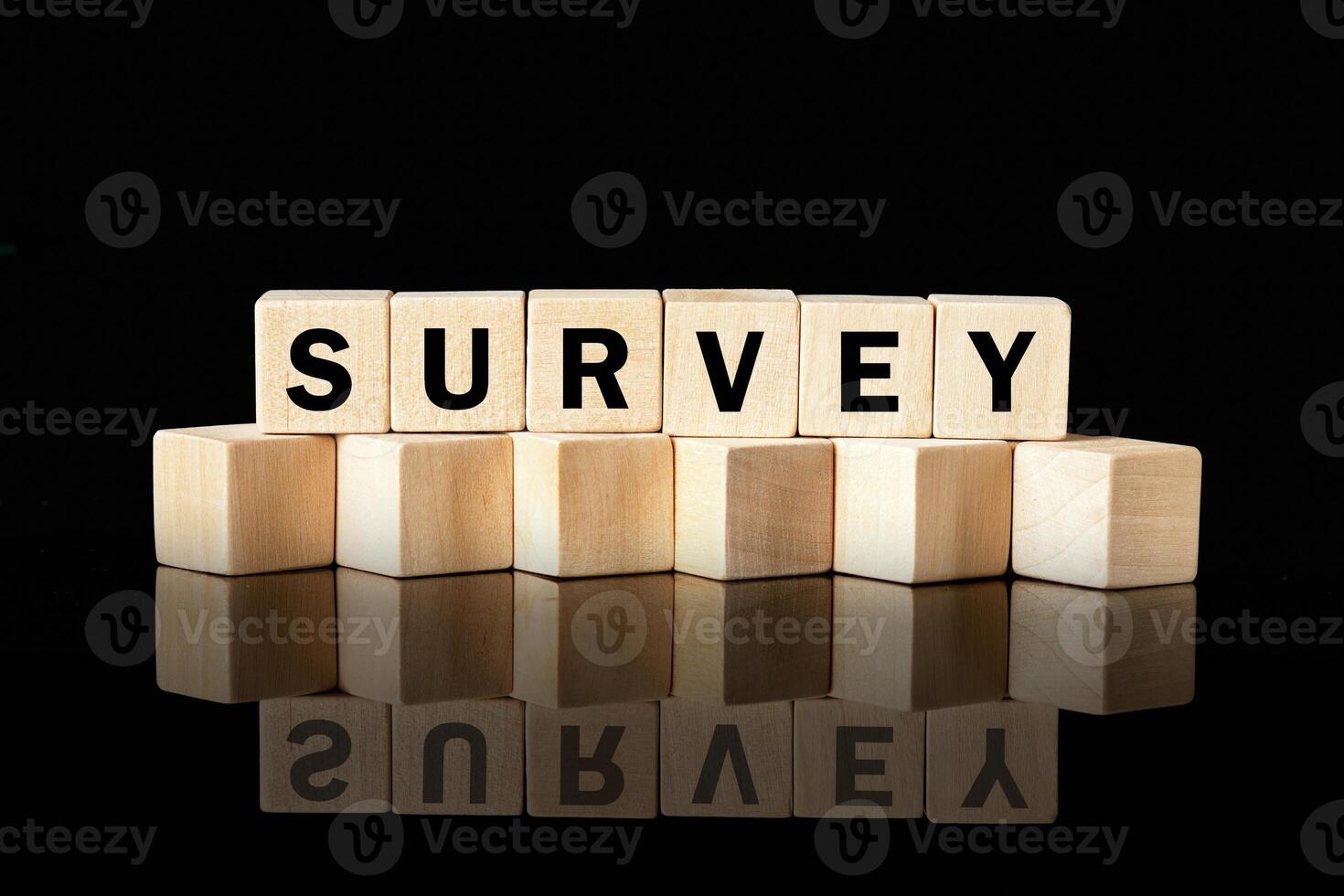 Wood blocks spell out the word SURVEY against a black background. The blocks reflect on the surface below, highlighting the importance of data collection and analysis photo