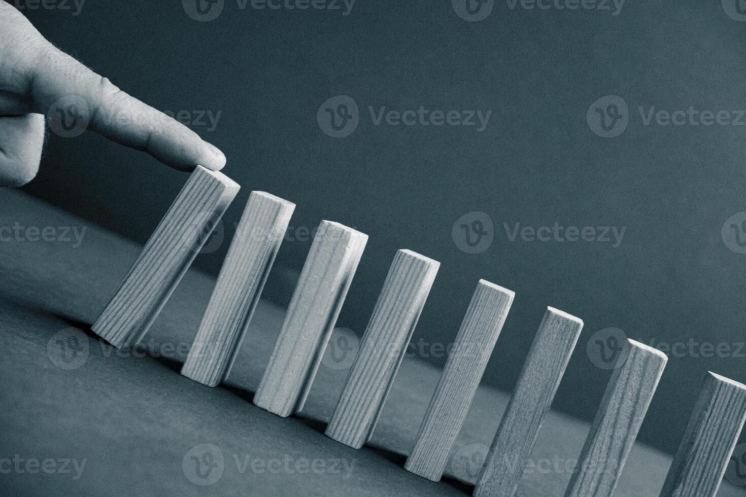 Domino has Fallen in Row. Domino theory. Effect. Hand with Finger is Pointing and Pushing the Falling Wood Blocks. Risk Management, Revolution Concept. Affect Business. Closeup. Manifestation. Red photo