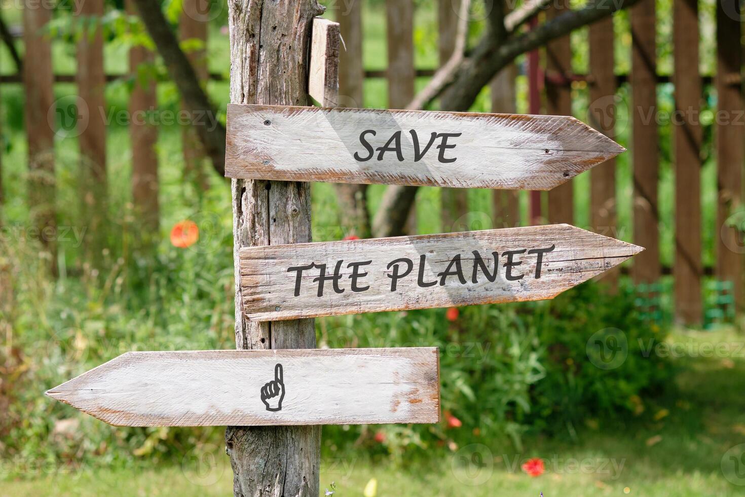 Three wooden arrow signs are attached to a weathered tree trunk. The signs read SAVE THE PLANET and one has a pointing finger, all encouraging action for environmental preservation photo