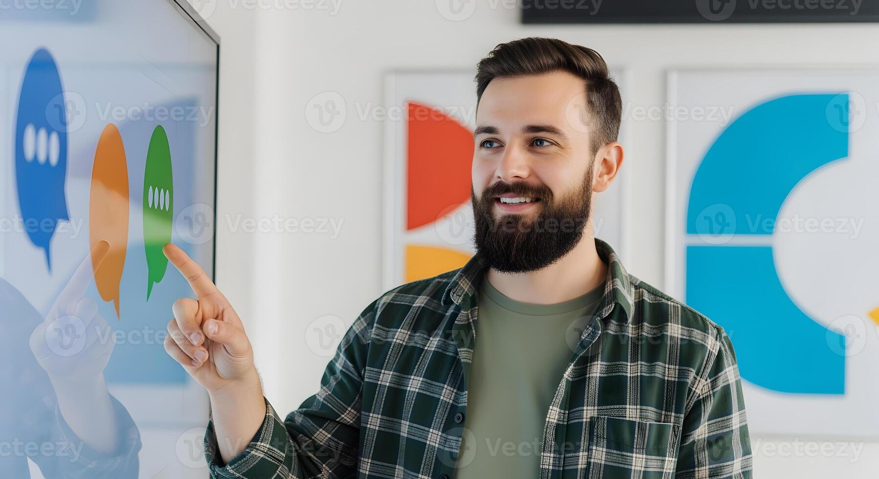 Smiling man pointing at interactive display with colorful speech bubbles and modern art photo
