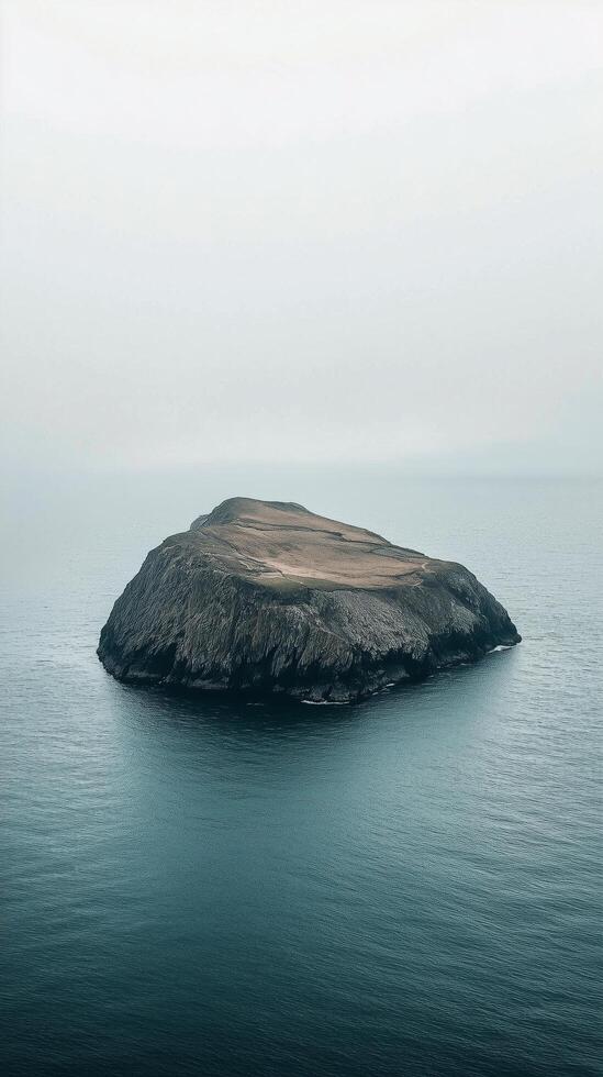 Remote island surrounded by calm waters under overcast sky at twilight photo