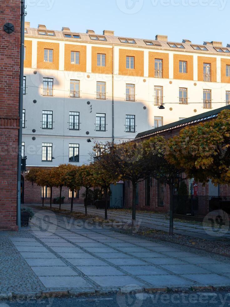 A brick building with a white facade and a row of trees in front of it photo