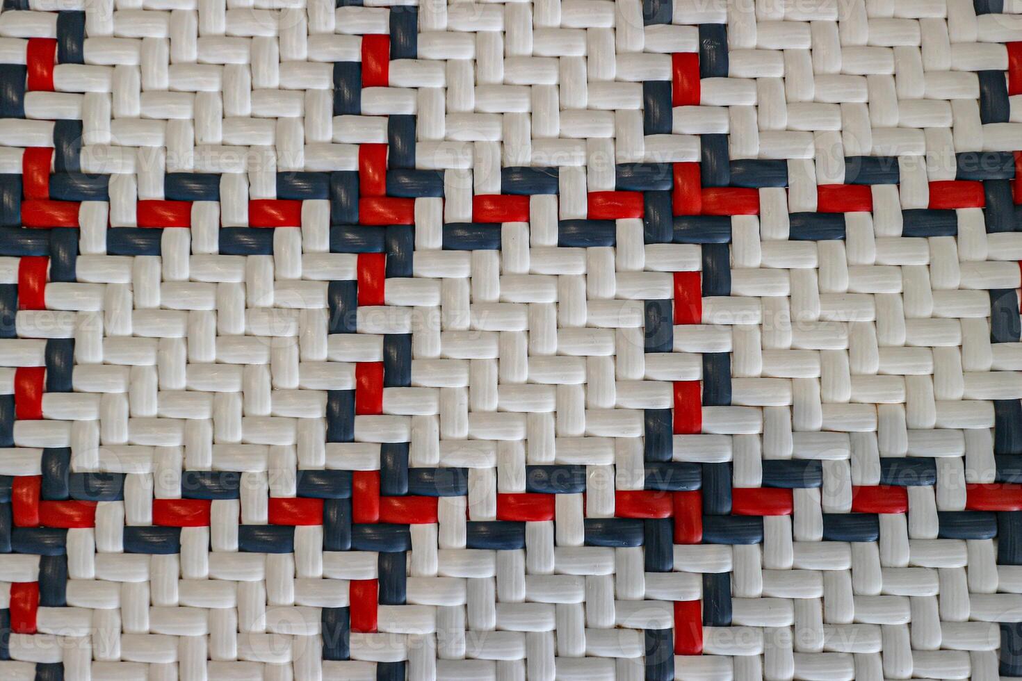 Close up abstract texture of woven plastic straps in a white red and blue checkered pattern Detailed geometric background ideal for digital texture overlay or textile concepts photo