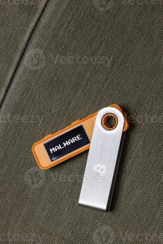 hardware Bitcoin wallet with Malware message on screen laying on fabric background photo