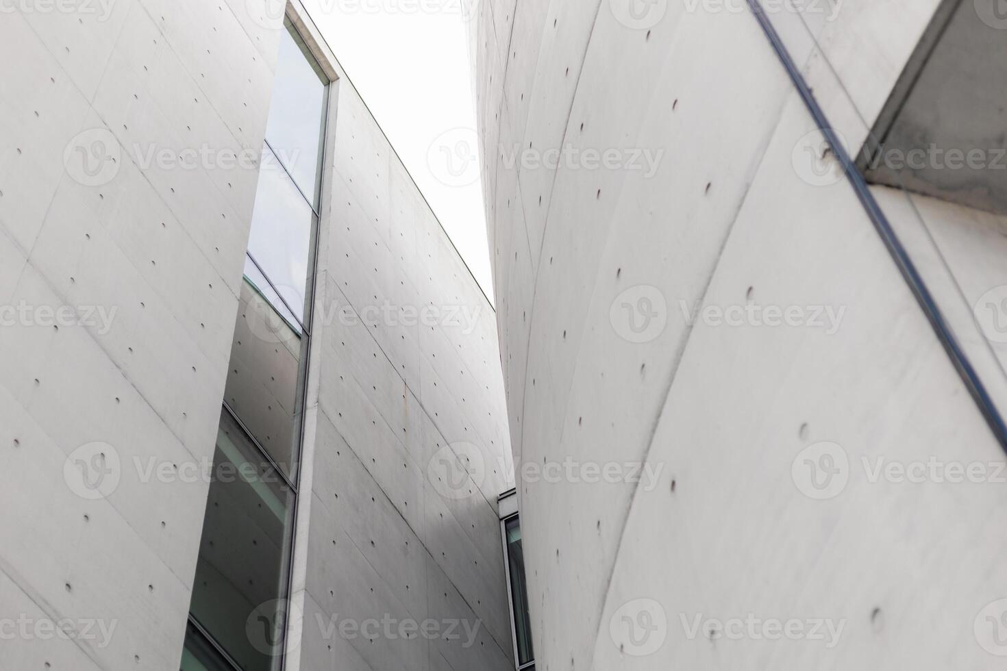 Structures with smooth concrete surfaces create an intriguing interplay of light and shadow. The design highlights angular forms and large glass elements, enhancing the modern aesthetic photo