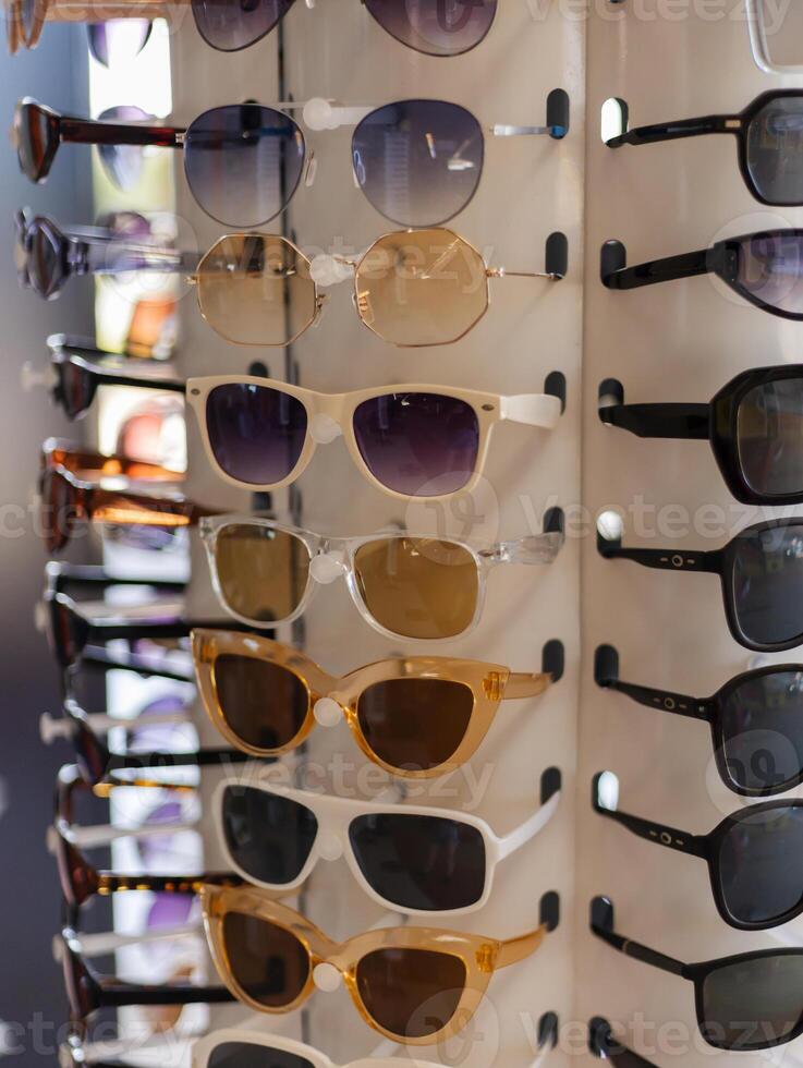 A selection of fashionable sunglasses is arranged on a display rack. The diverse styles include different shapes and shades, appealing to various tastes. Perfect for summer photo