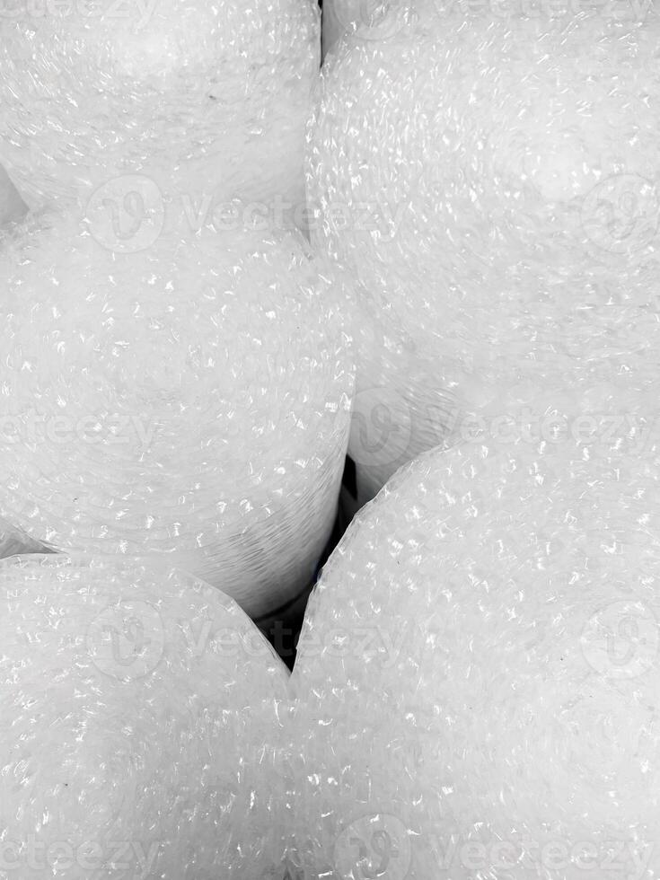 Rolls of translucent bubble wrap creating an abstract pattern with small air pockets, used for cushioning and protecting items during shipping and storage. Decorative background for design photo