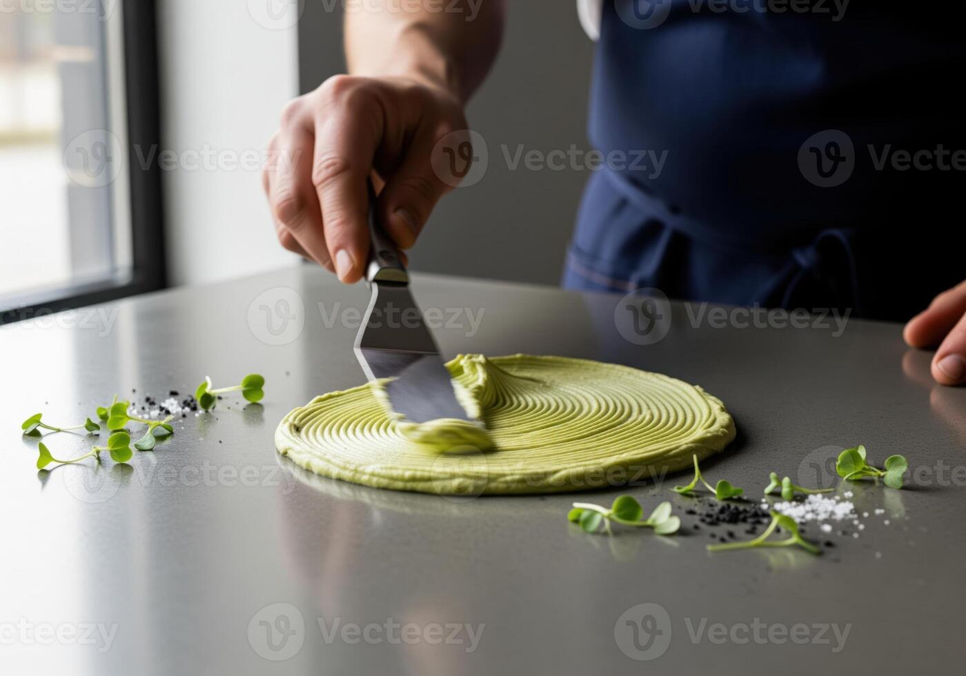 Close up of a chef using a spatula to spread green avocado cream for plating. photo