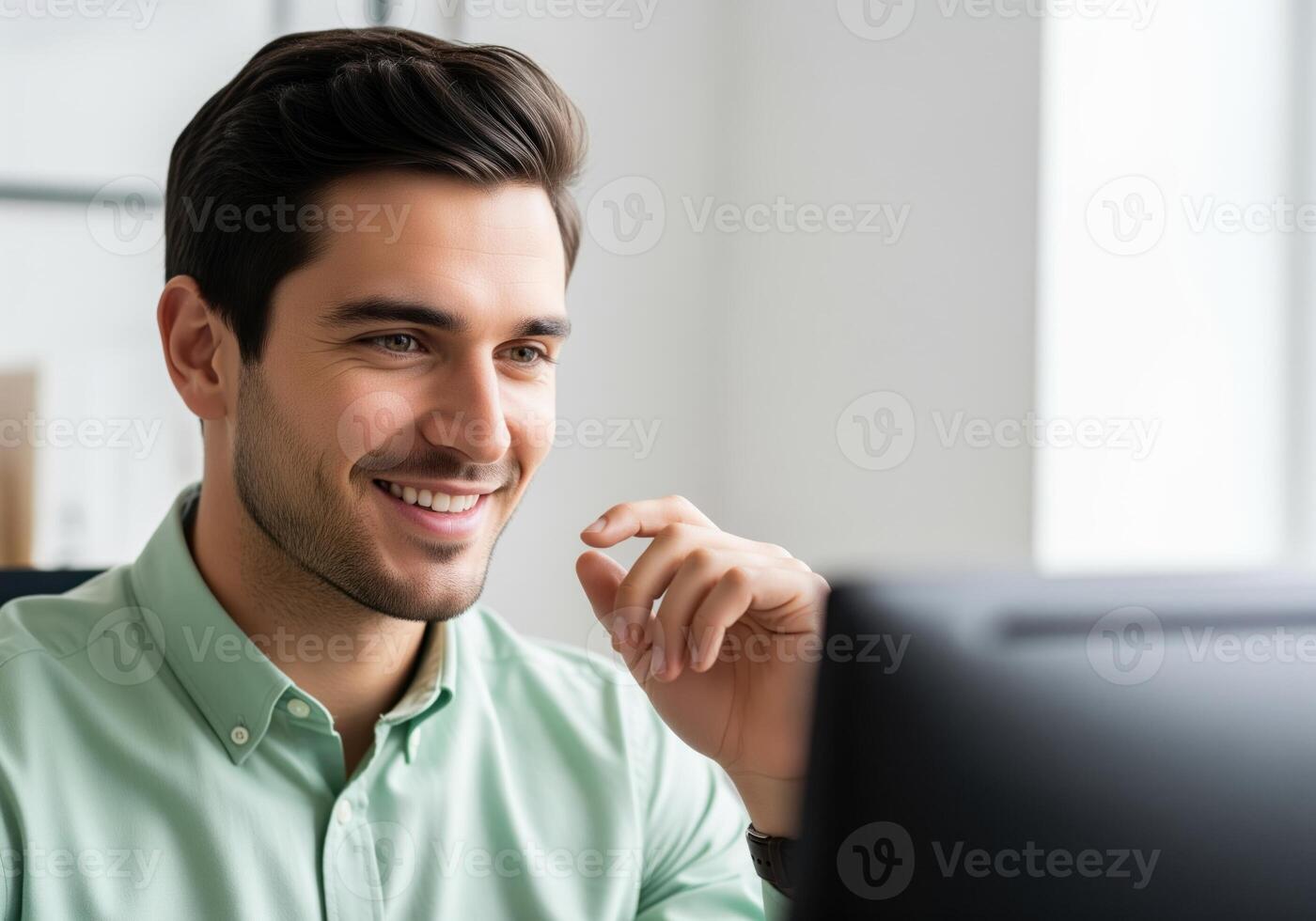 Confident young professional man smiling while working on computer in a modern office photo