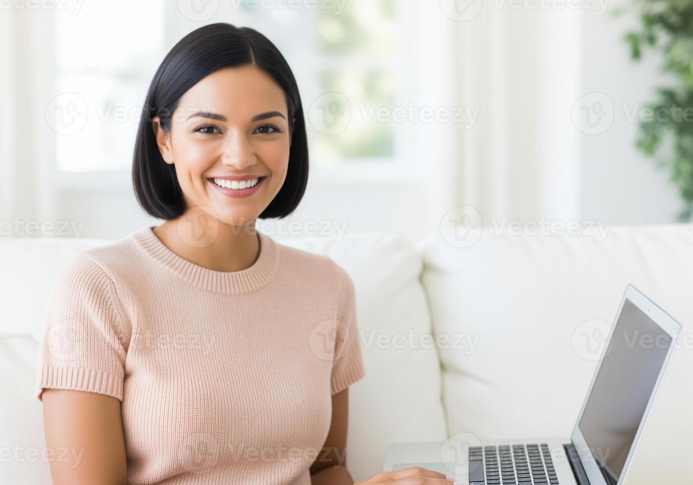 Happy young woman smiling brightly while working or browsing on a laptop computer at home. photo