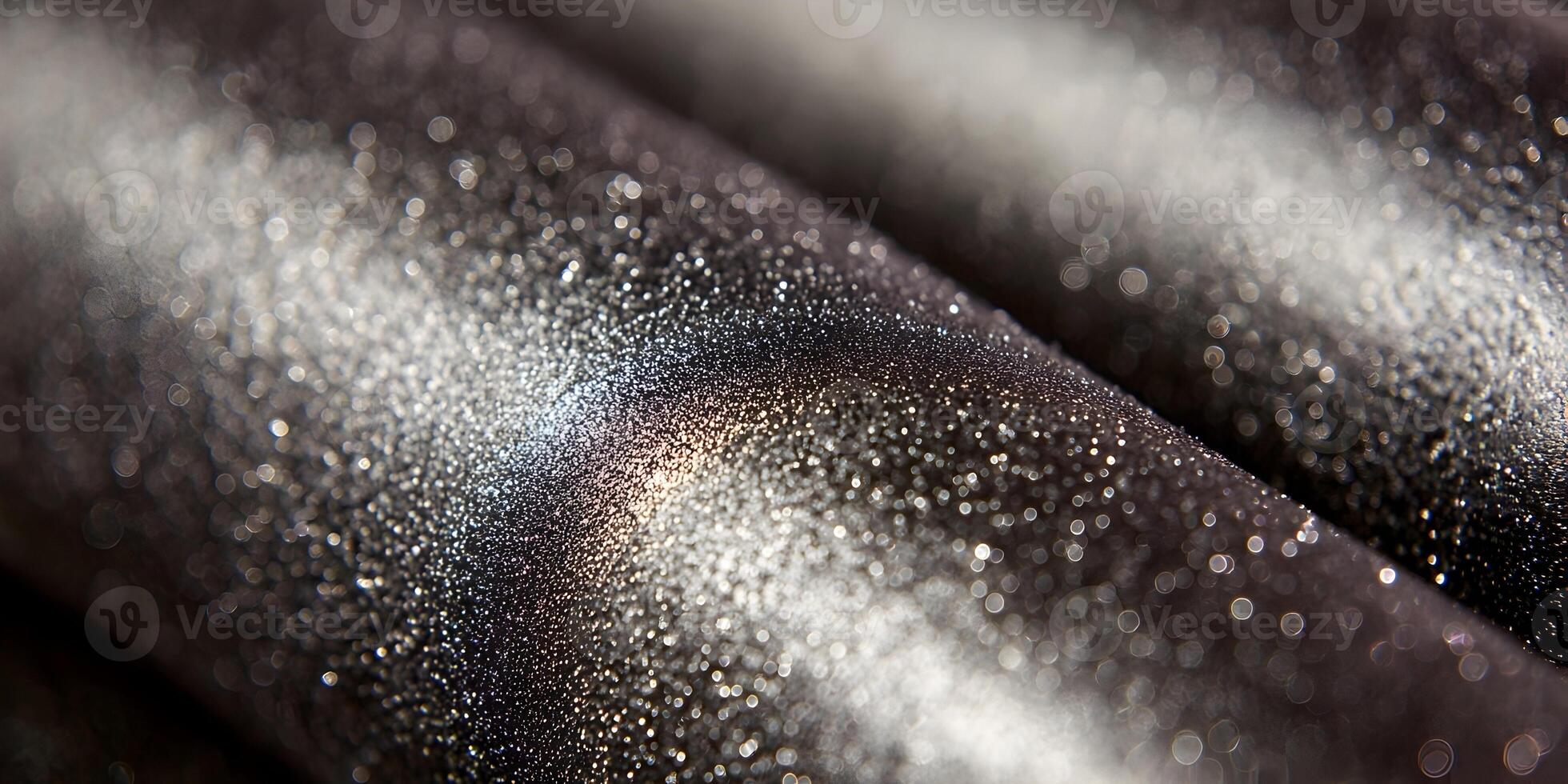A close up view reveals a dark surface with sparkling silver particles reflecting light in an abstract pattern photo