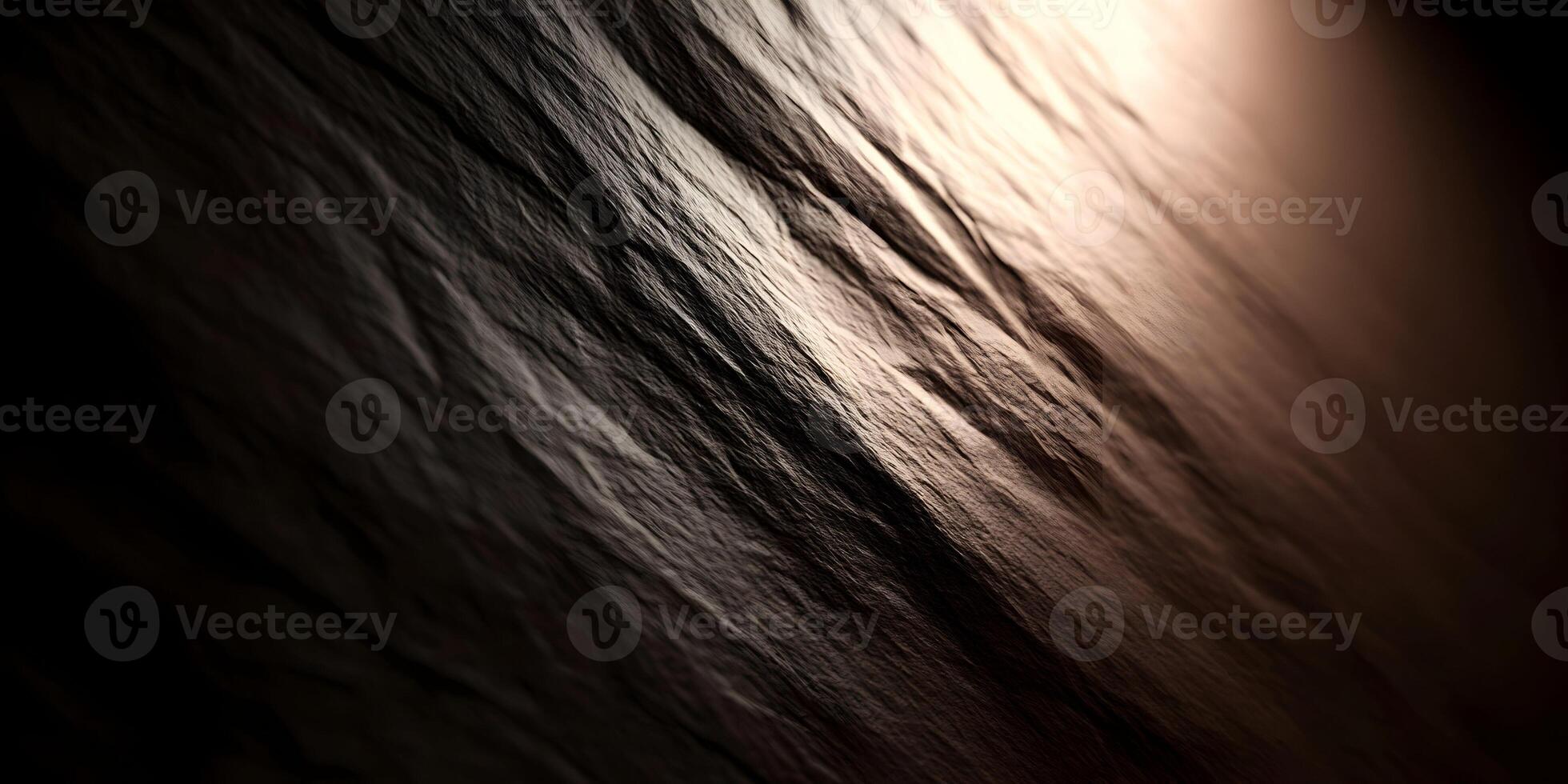 A dark rough textured surface is dramatically illuminated by a warm diagonal light creating deep shadows photo