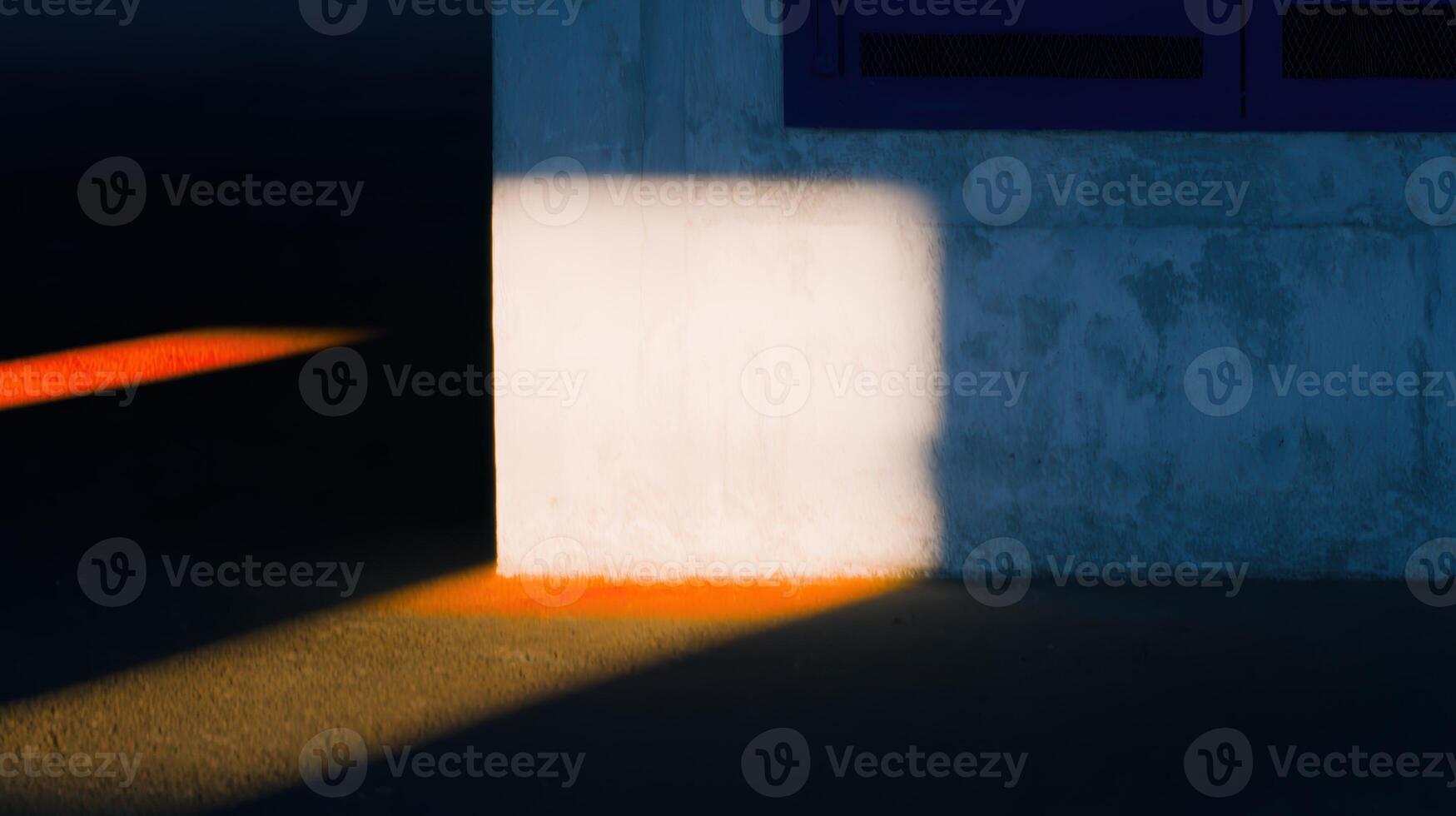Shadows and light create patterns on pavement by a wall photo