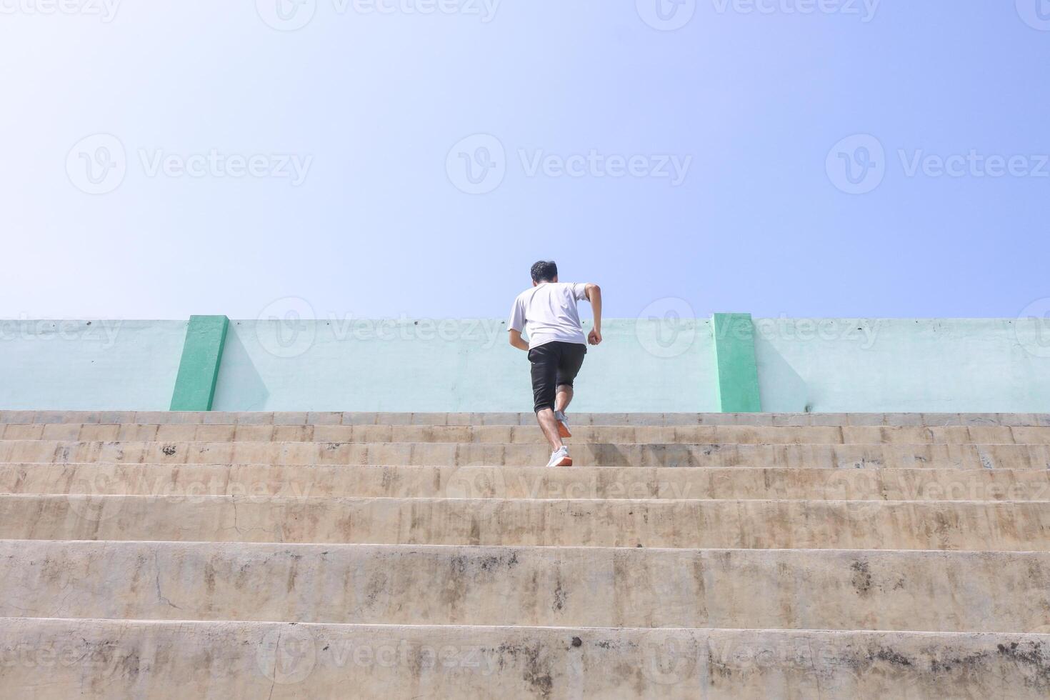 A man is running up a set of stairs. Concept of determination and perseverance as the man pushes himself to reach the top of the steps. The, man's focused expression, photo