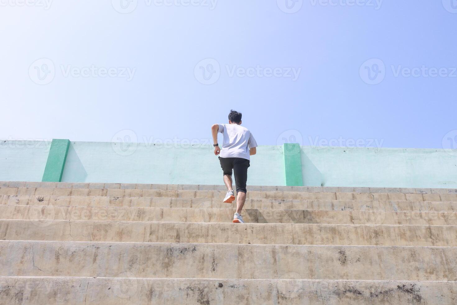 A man is running up a set of stairs. Concept of determination and perseverance as the man pushes himself to reach the top of the steps. The man's, focused expression photo