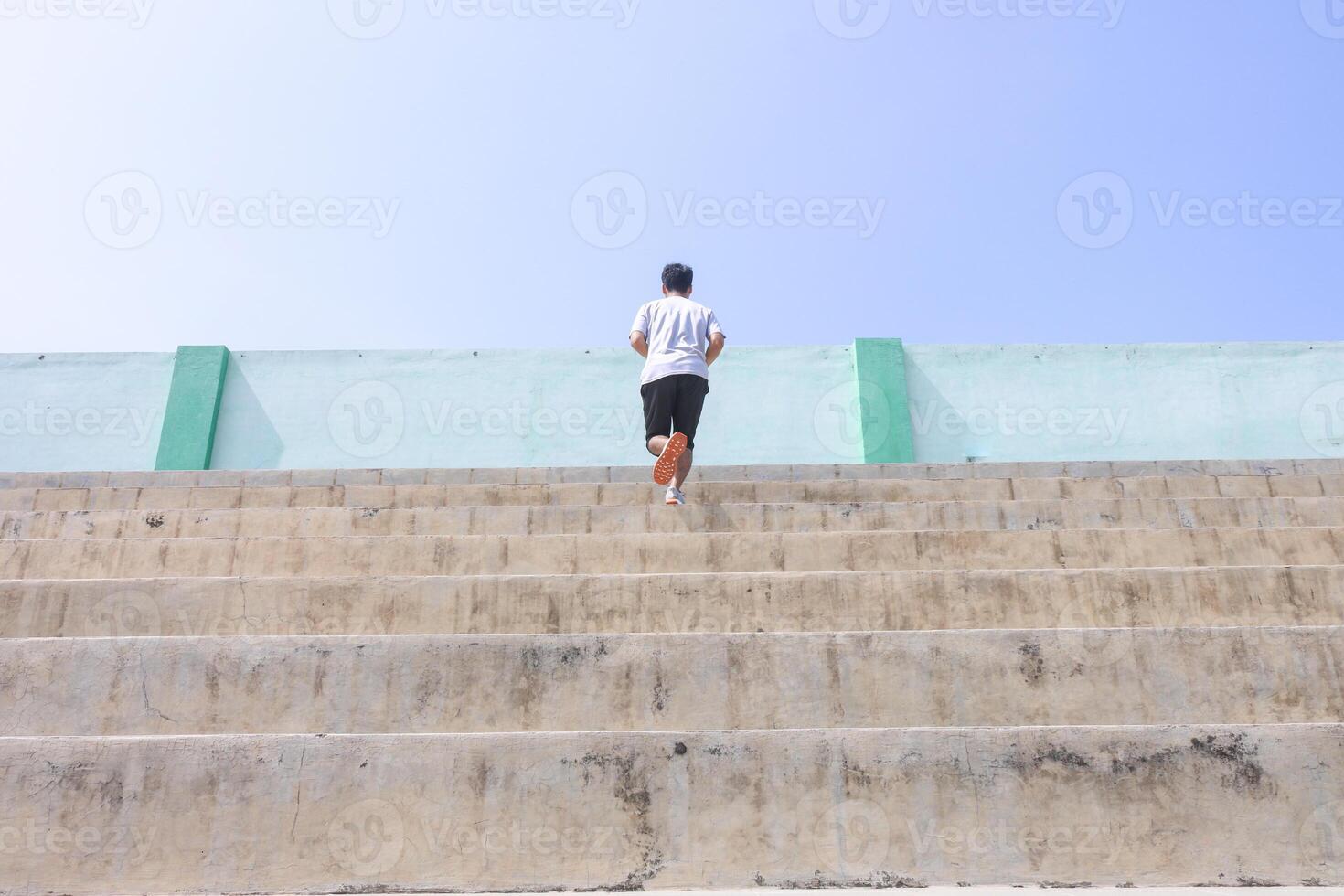 A man is running up a set of stairs. Concept of determination and perseverance as the man pushes himself to reach the top of the steps. The man's focused expression. photo
