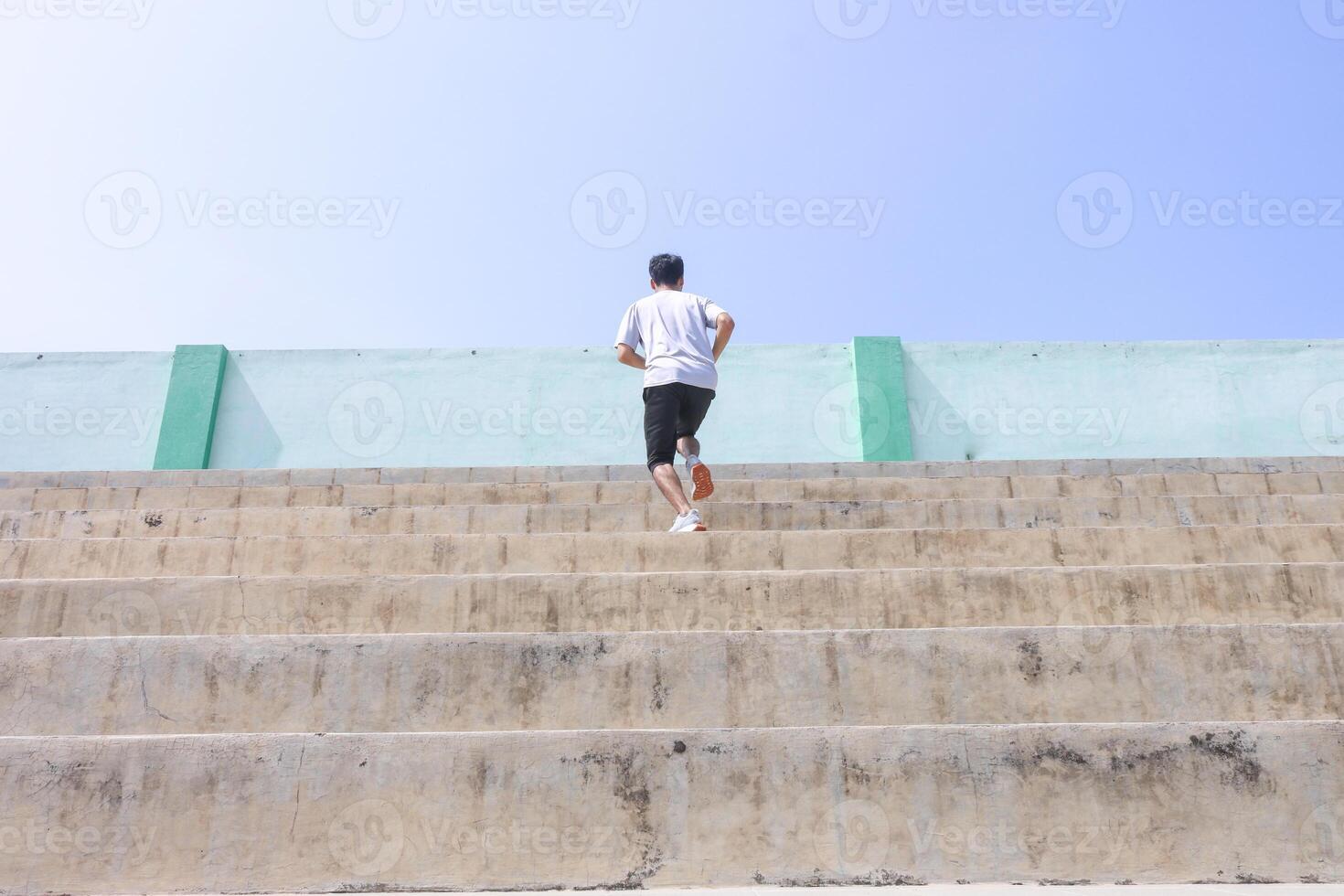A man is running up a set of stairs. Concept of determination and perseverance as the man pushes himself to reach the top of the steps. The man's focused, expression photo
