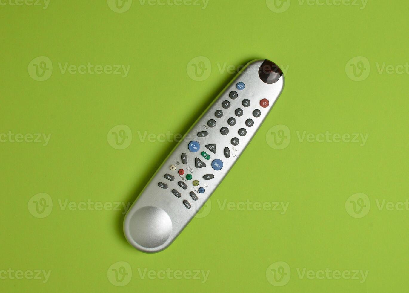 Multi-function push-button TV remote control on a green paper background. Top view. photo