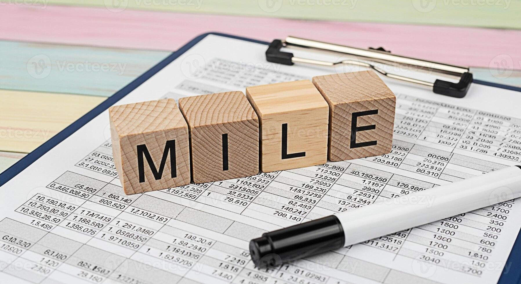 Wooden blocks spelling MILE on financial data sheet representing business goals and achievement in a corporate setting symbolizing success and progress in a competitive environment with a positive moo photo
