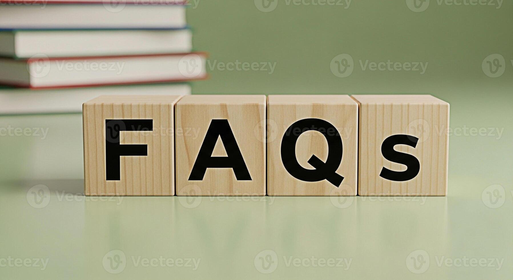 Wooden blocks spelling FAQs on a green surface with a stack of books in the background representing information access knowledge resources and a helpful informative atmosphere for learning and problem photo