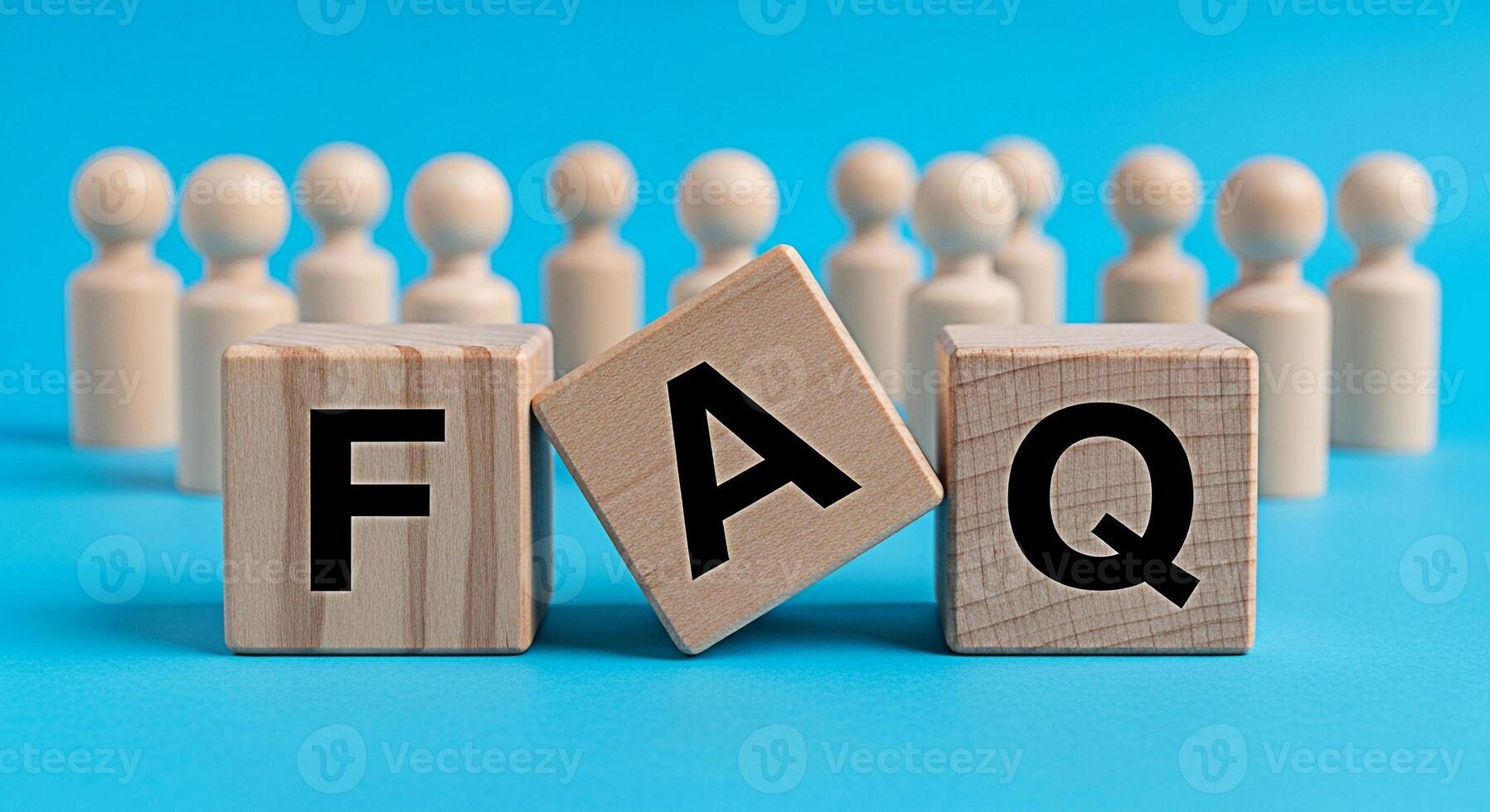 Wooden blocks spelling FAQ on a blue surface with blurred figures in the background representing frequently asked questions and providing answers in a clear and concise manner conveying simplicity and photo