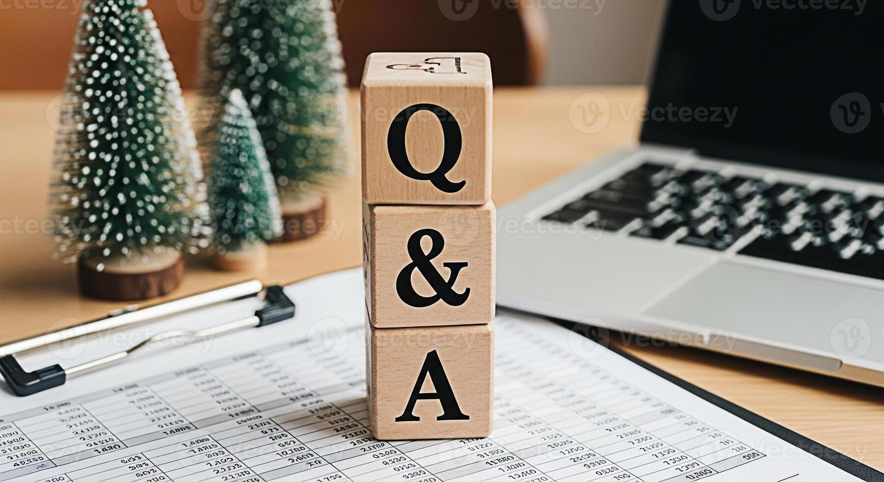 Wooden blocks spelling QA on a desk with financial reports and a laptop representing question and answer sessions in a business setting fostering a sense of clarity and problemsolving during the holid photo