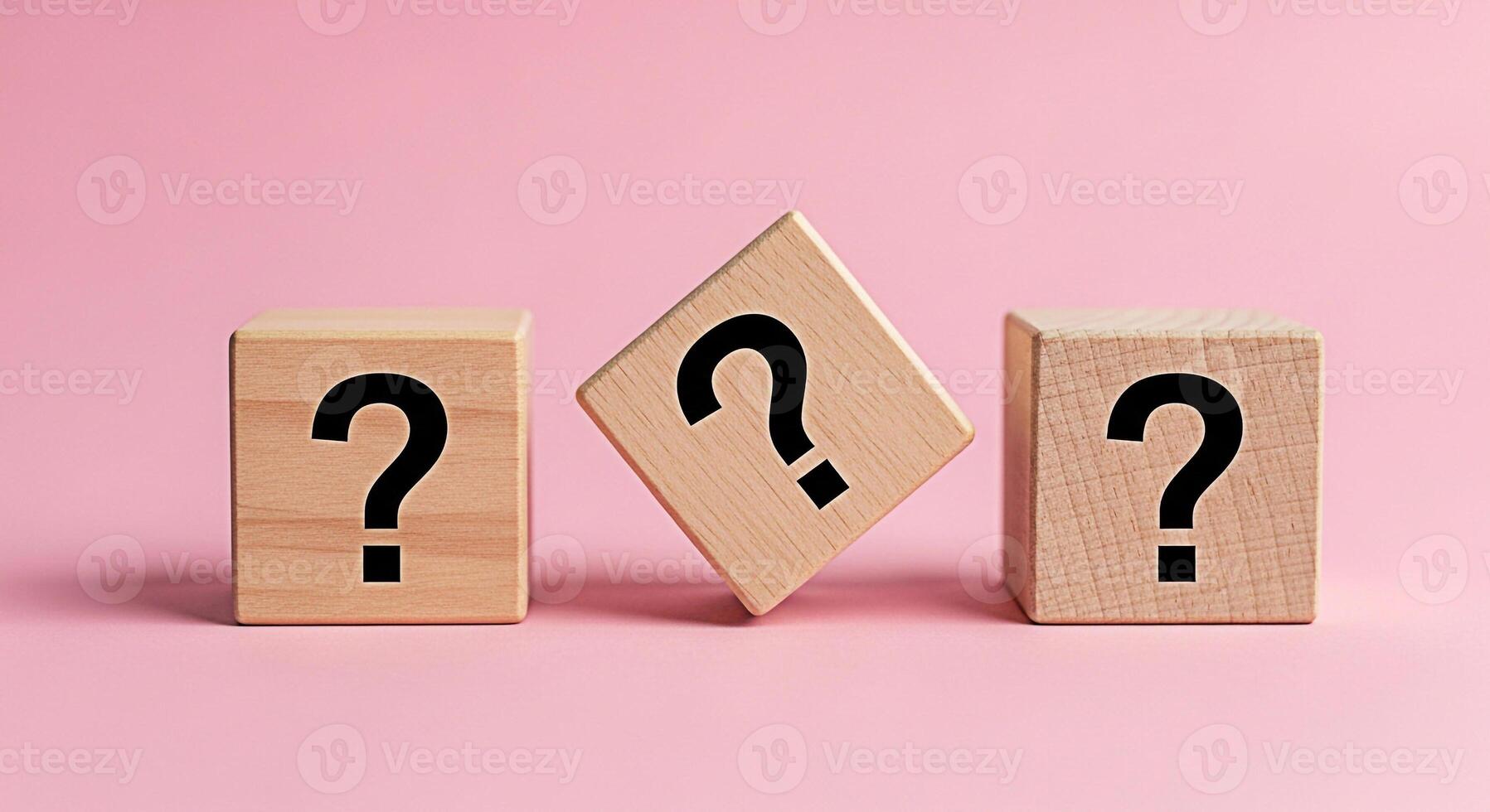 Three wooden cubes displaying question marks on a pink background representing uncertainty and the need for answers in a simple minimalist studio setting evoking curiosity and problemsolving photo