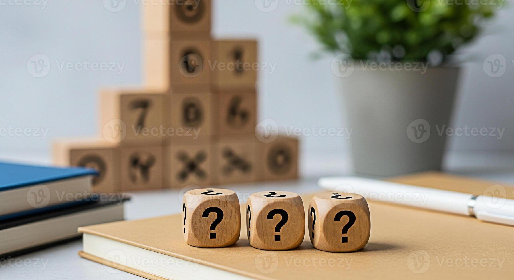 Three wooden dice displaying question marks resting on a tan notebook in a bright modern office setting representing uncertainty problemsolving and the search for answers in business and education photo