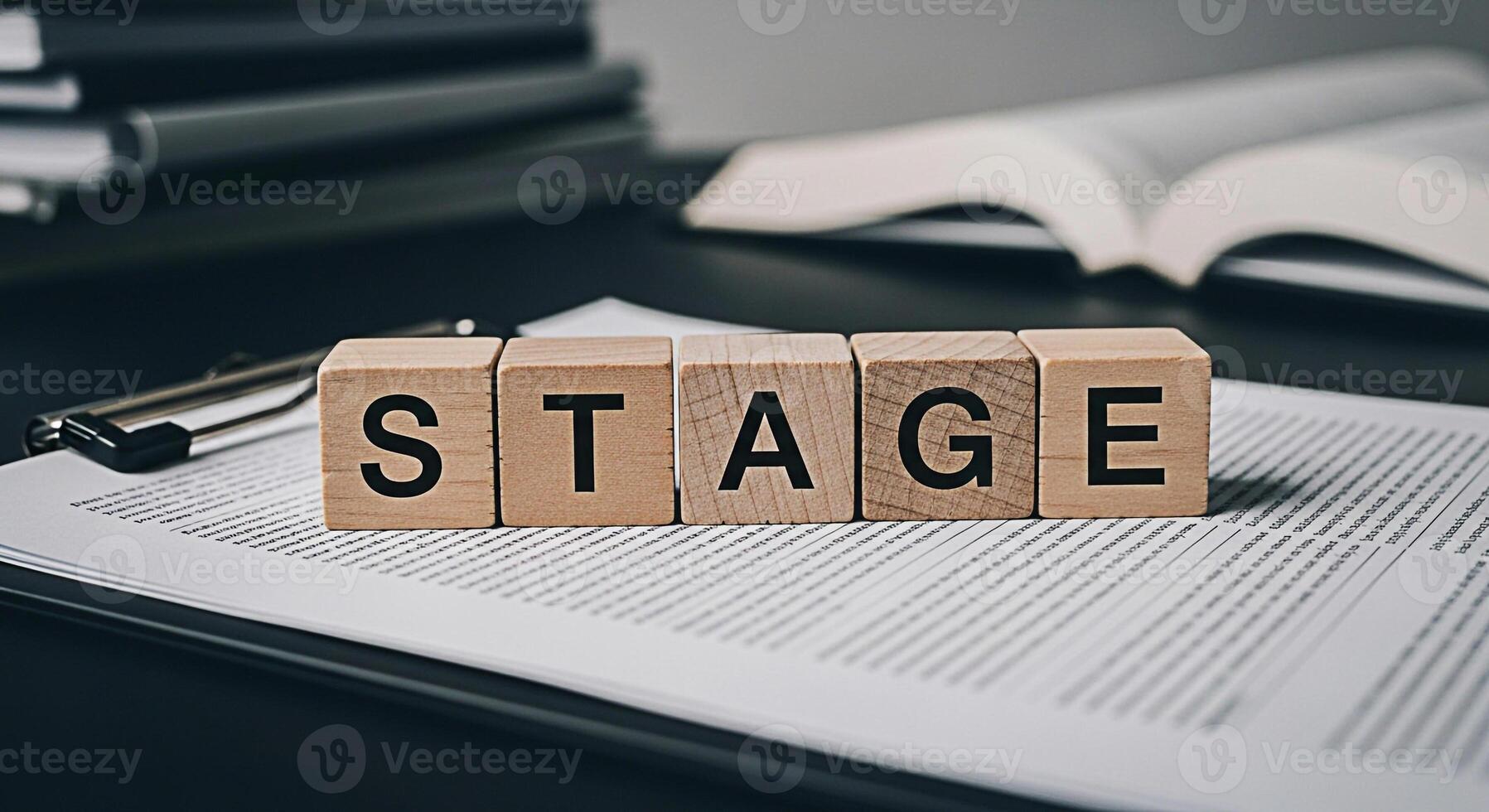 Wooden blocks spelling STAGE resting on a document on a dark desk symbolizing progress and development in a professional setting conveying a sense of planning preparation and advancement towards goals photo