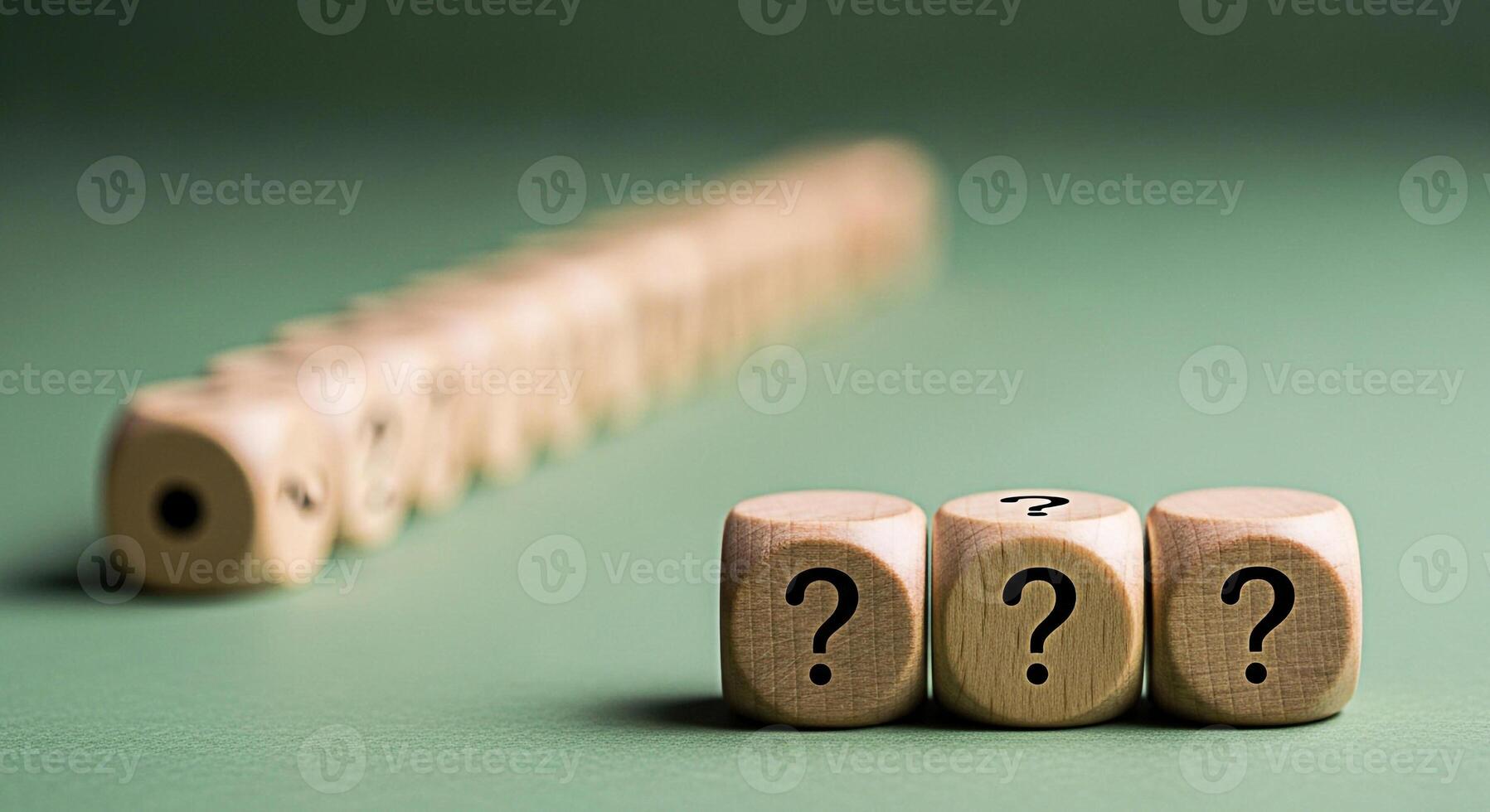 Three wooden dice displaying question marks on a green surface representing uncertainty and the search for answers in a conceptual and thoughtprovoking setting with a row of blurred dice in the backgr photo