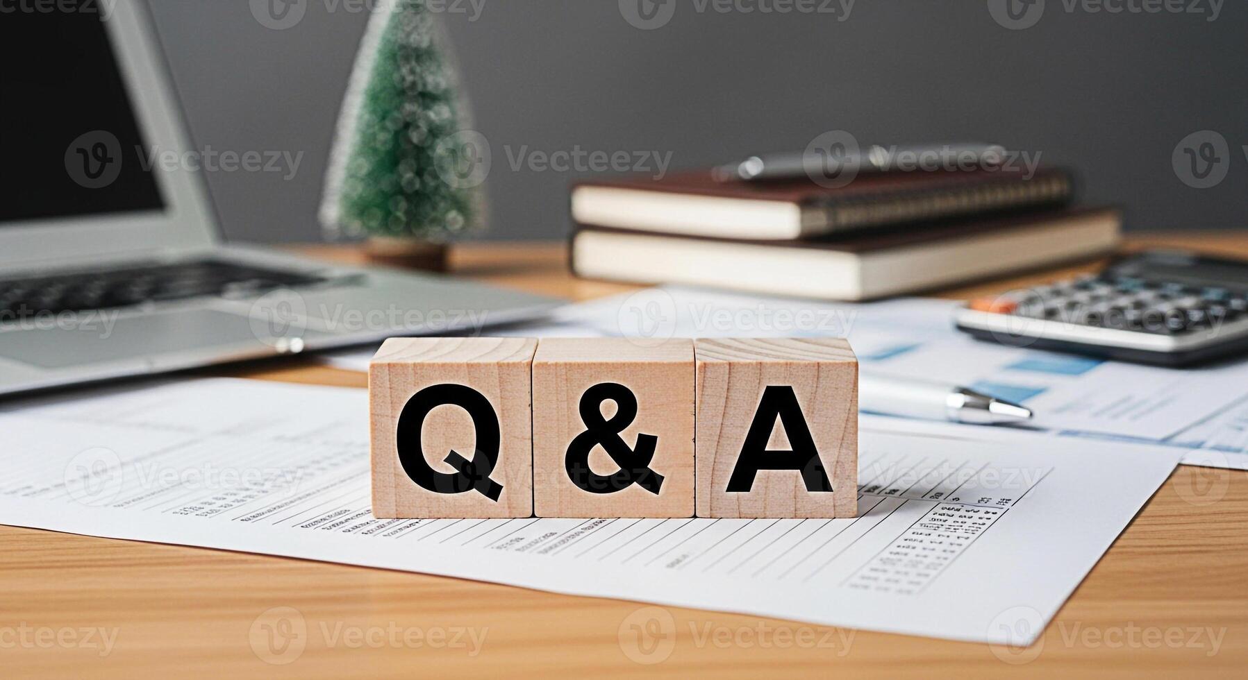 Wooden blocks displaying Q A on a wooden desk in a modern office environment symbolizing knowledge sharing and problemsolving with a laptop documents calculator and books in the background photo