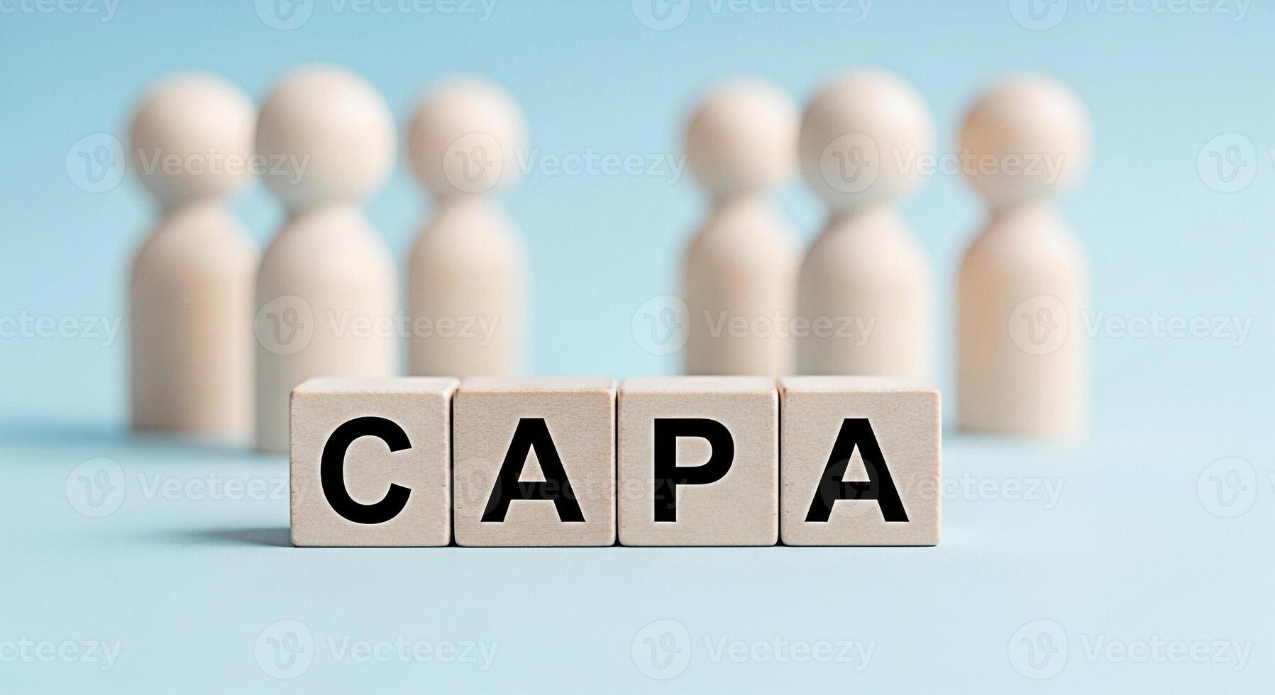 Wooden figures standing behind CAPA blocks on a light blue background representing corrective and preventive action for quality control and continuous improvement in a business or manufacturing settin photo