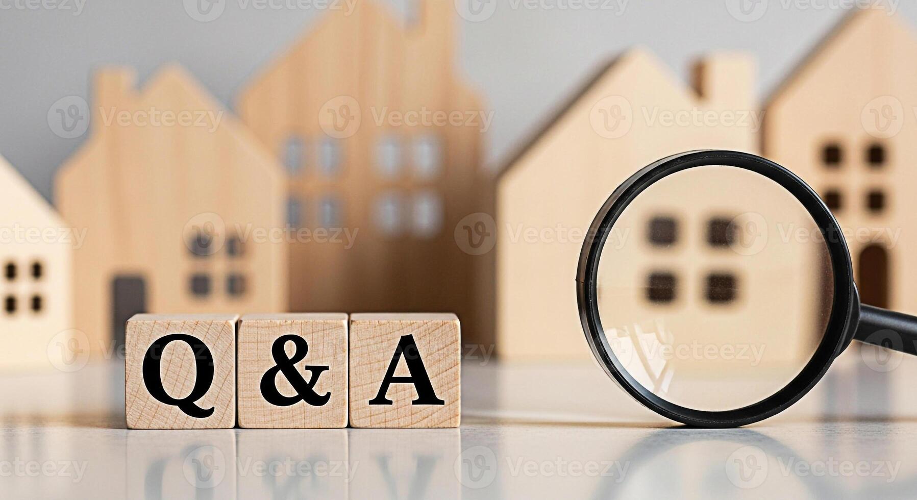 Wooden blocks displaying Q A with a magnifying glass examining miniature house models on a reflective surface representing real estate questions and answers in a bright informative setting photo