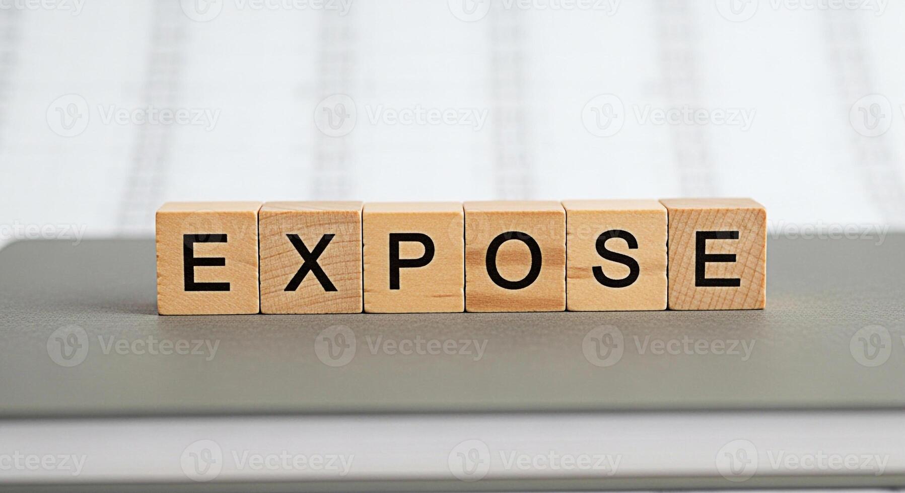 Wooden blocks spelling EXPOSE on a gray surface in a bright studio symbolizing transparency revelation and the importance of uncovering hidden truths in business and personal life photo