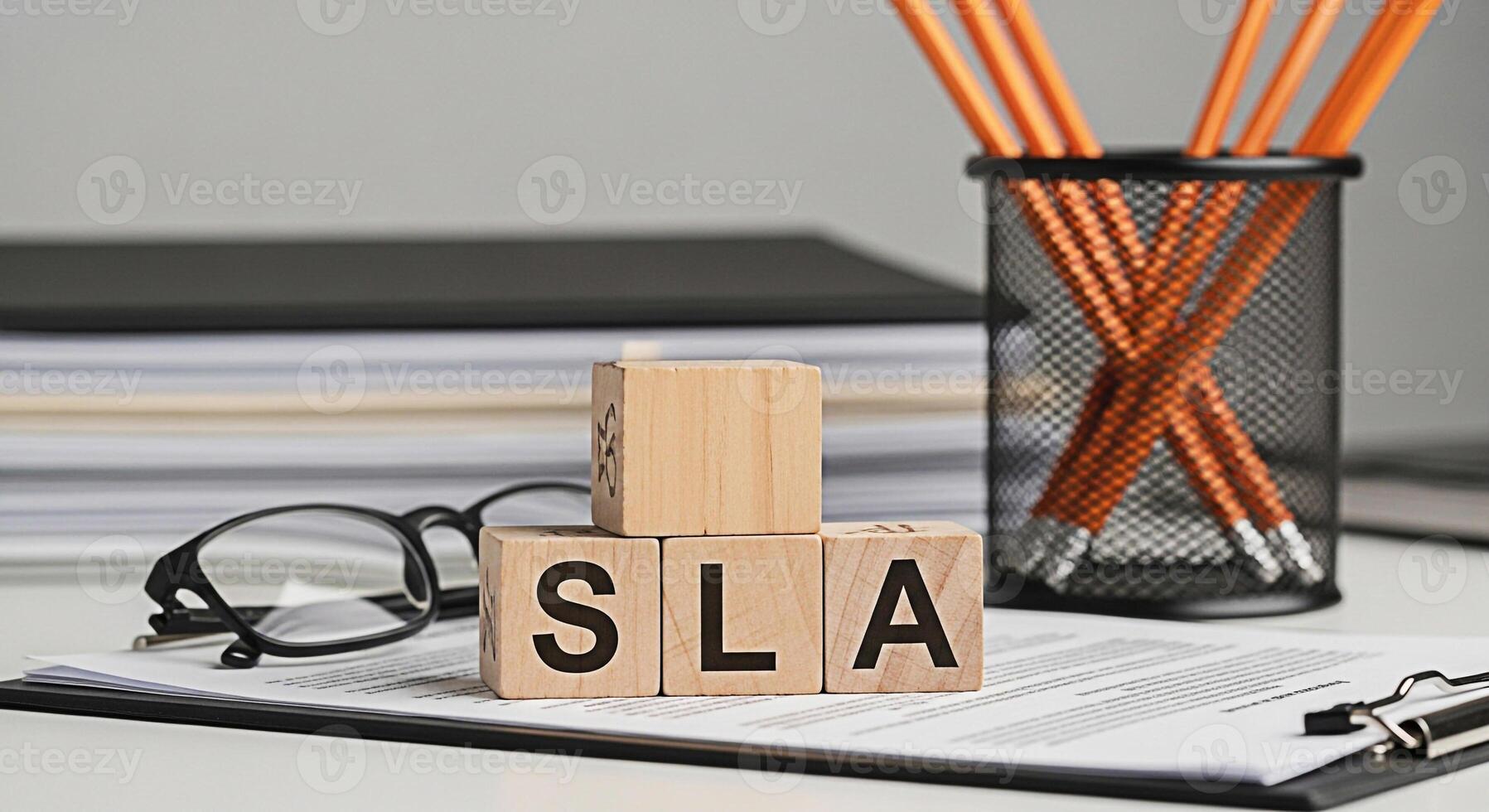 Wooden blocks spelling SLA on a desk with documents and pencils representing Service Level Agreement in a professional office environment emphasizing business terms and commitment to quality service photo