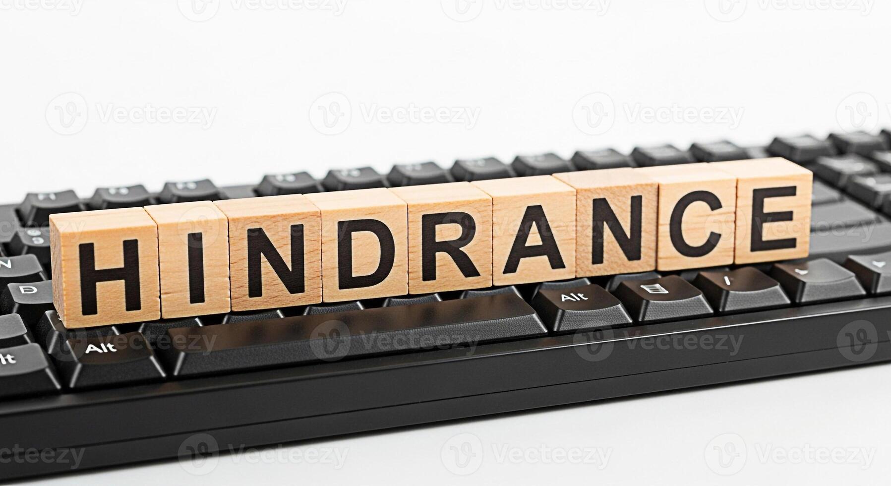 Wooden blocks spelling HINDRANCE resting on a black computer keyboard symbolizing obstacles and challenges in technology and business creating a mood of frustration and problemsolving photo
