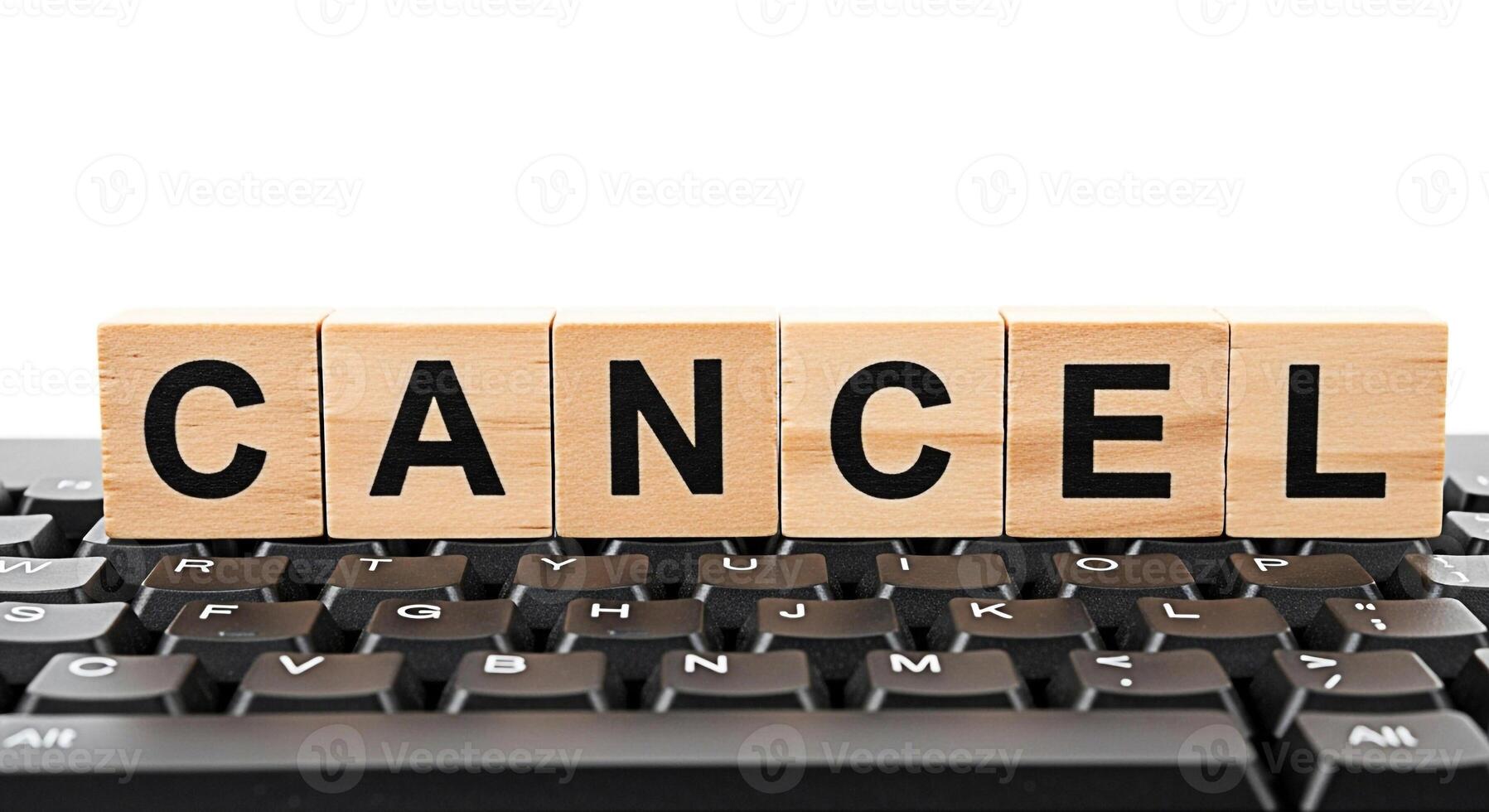 Wooden blocks spelling CANCEL sitting atop a black computer keyboard symbolizing termination cancellation or the end of a process in a digital environment conveying a sense of finality and decision photo