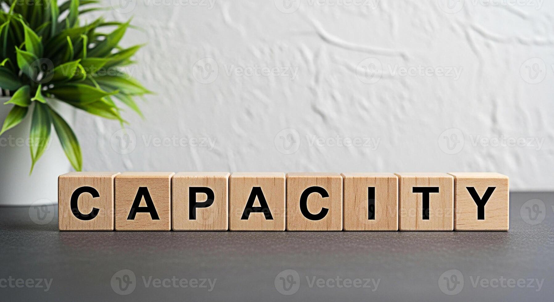 Wooden blocks spelling CAPACITY on a dark surface in a bright minimalist office setting representing business potential resource management and the ability to handle workload with efficiency and growt photo