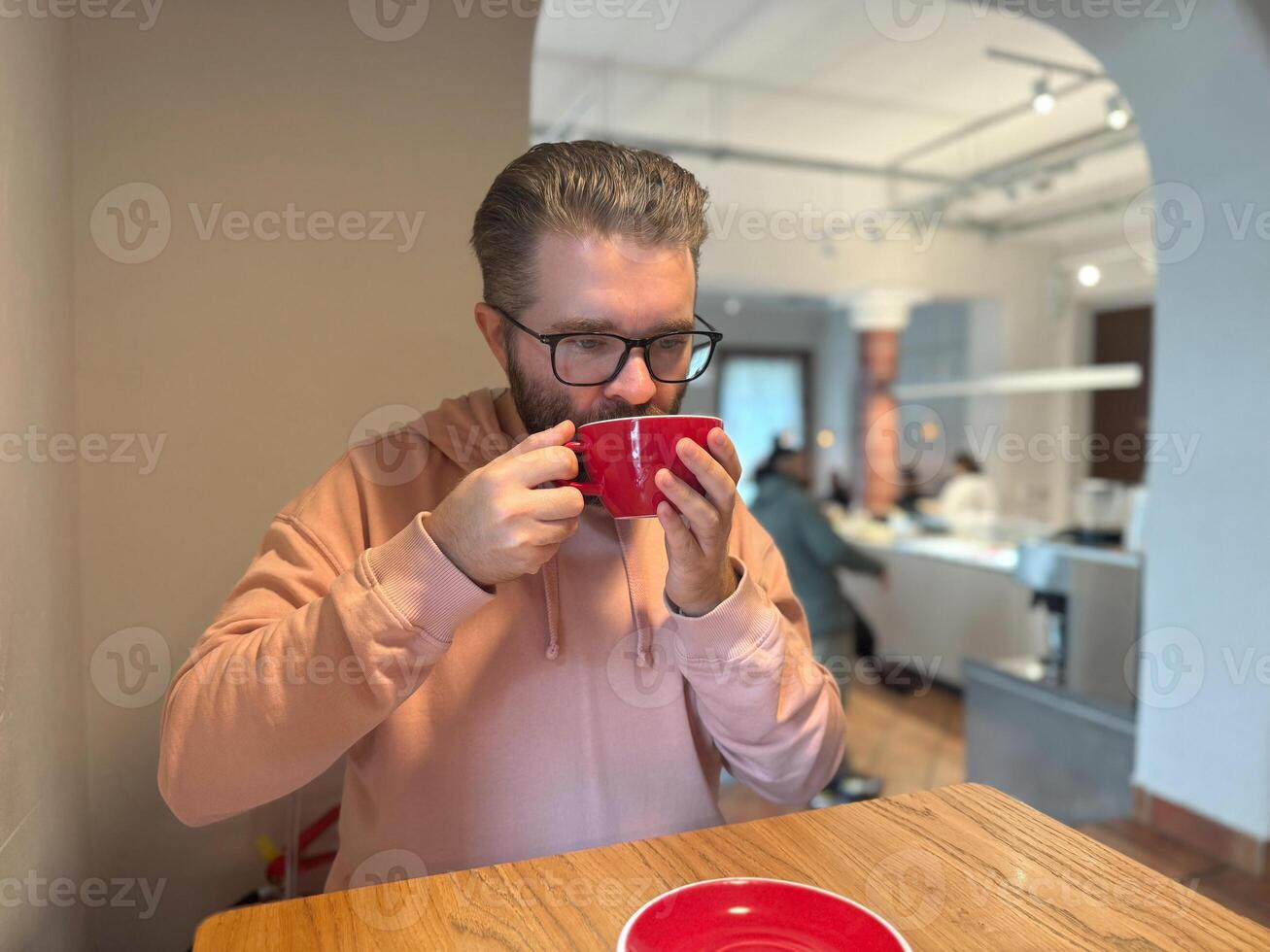 Man drinking coffee at cafe table. Quiet moment of warmth, reflection and simple pleasure during daily routine. photo