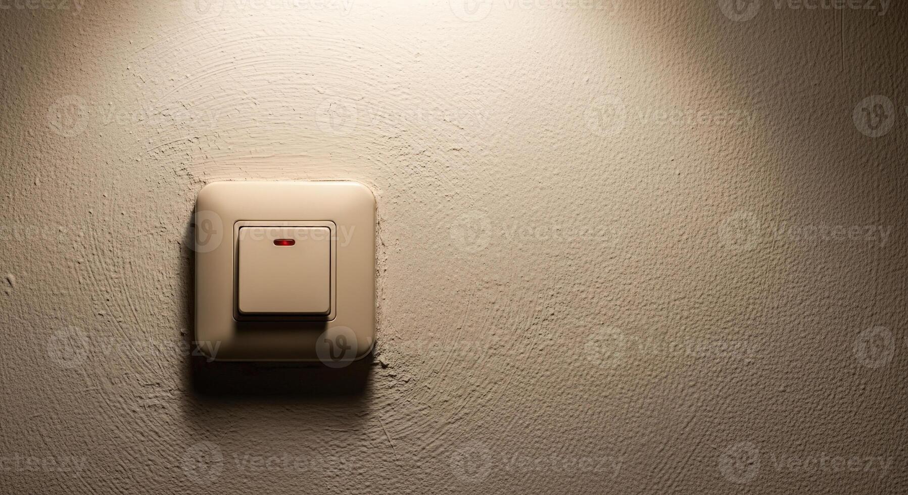 A cream colored light switch on a textured wall with a red indicator light glowing in a dimly lit room photo
