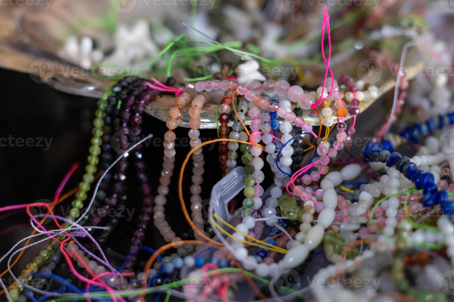 Colorful array of beads and threads displayed in a handcrafted bowl at a local market photo