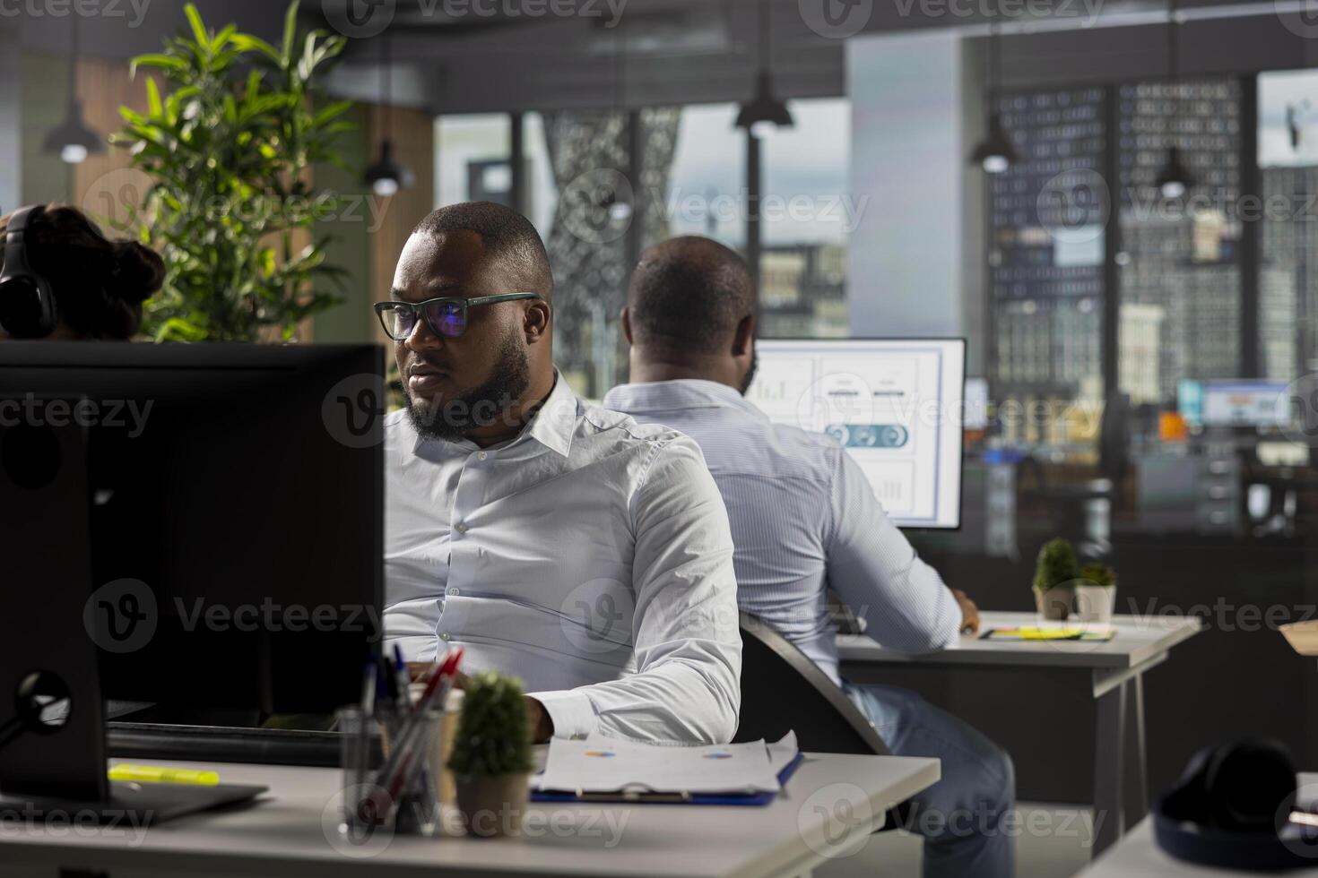 Multiethnic work team reviewing analytics and forecasting on computers, focusing on performance metrics and report writing. Data visualization to support growth and management decisions. photo