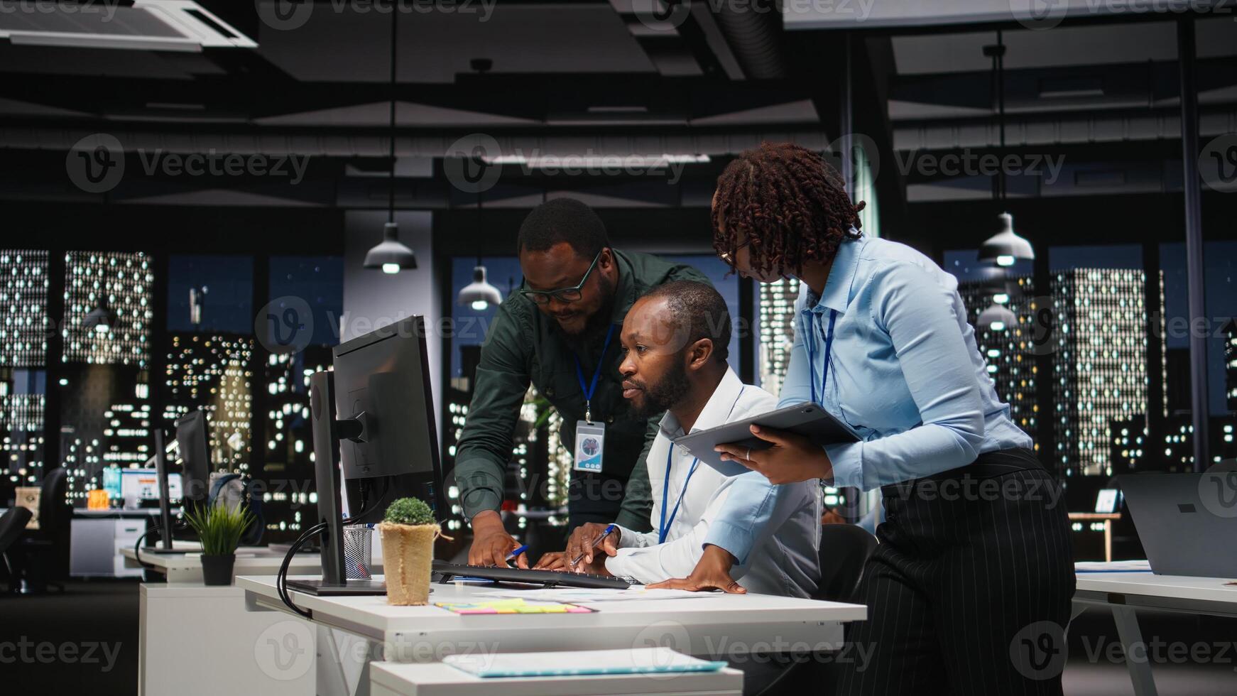 Group of black employees doing teamwork on important task late at night, collaborating on building a new development strategy after hours. Reviewing insights to enhance efficiency. photo