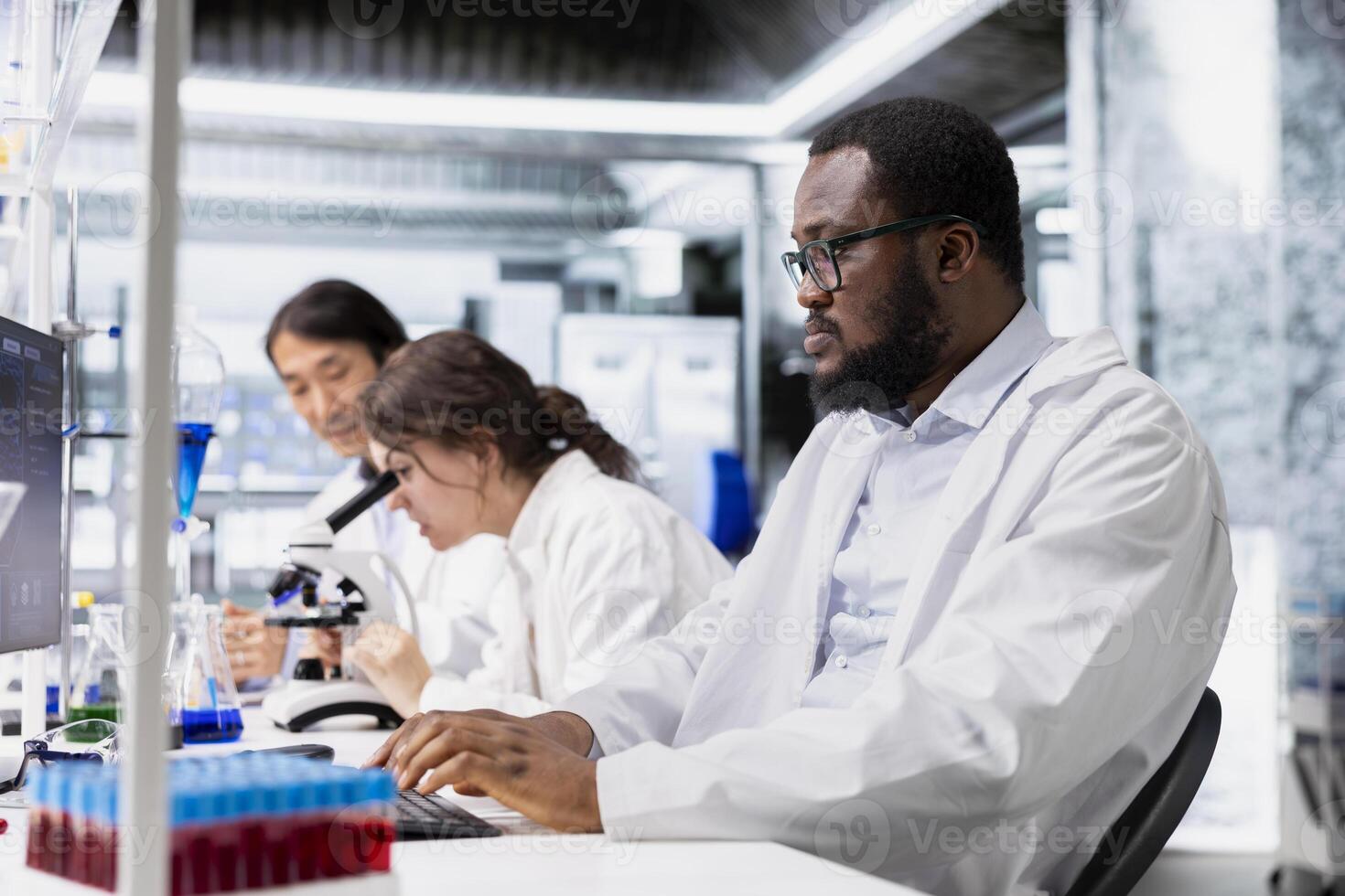Laboratory molecular biologist using computer software to process DNA patient data for clinical research. African american man uses PC program to do lab genetic analysis diagnostics photo