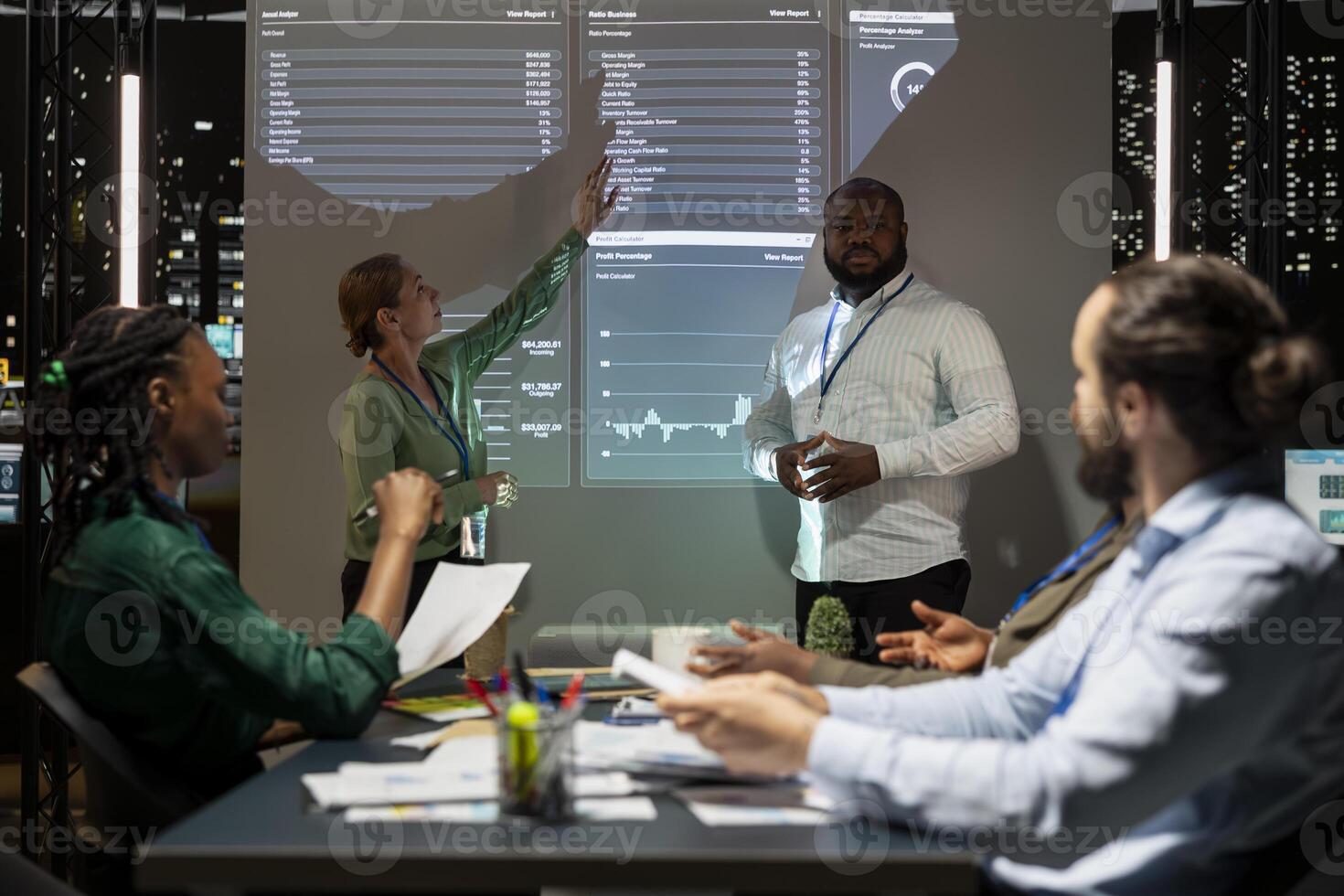 Business colleagues evaluating performance indicators within the company, conducting a forecast session at night and discuss training programs. Workers team enhancing productivity at night. photo