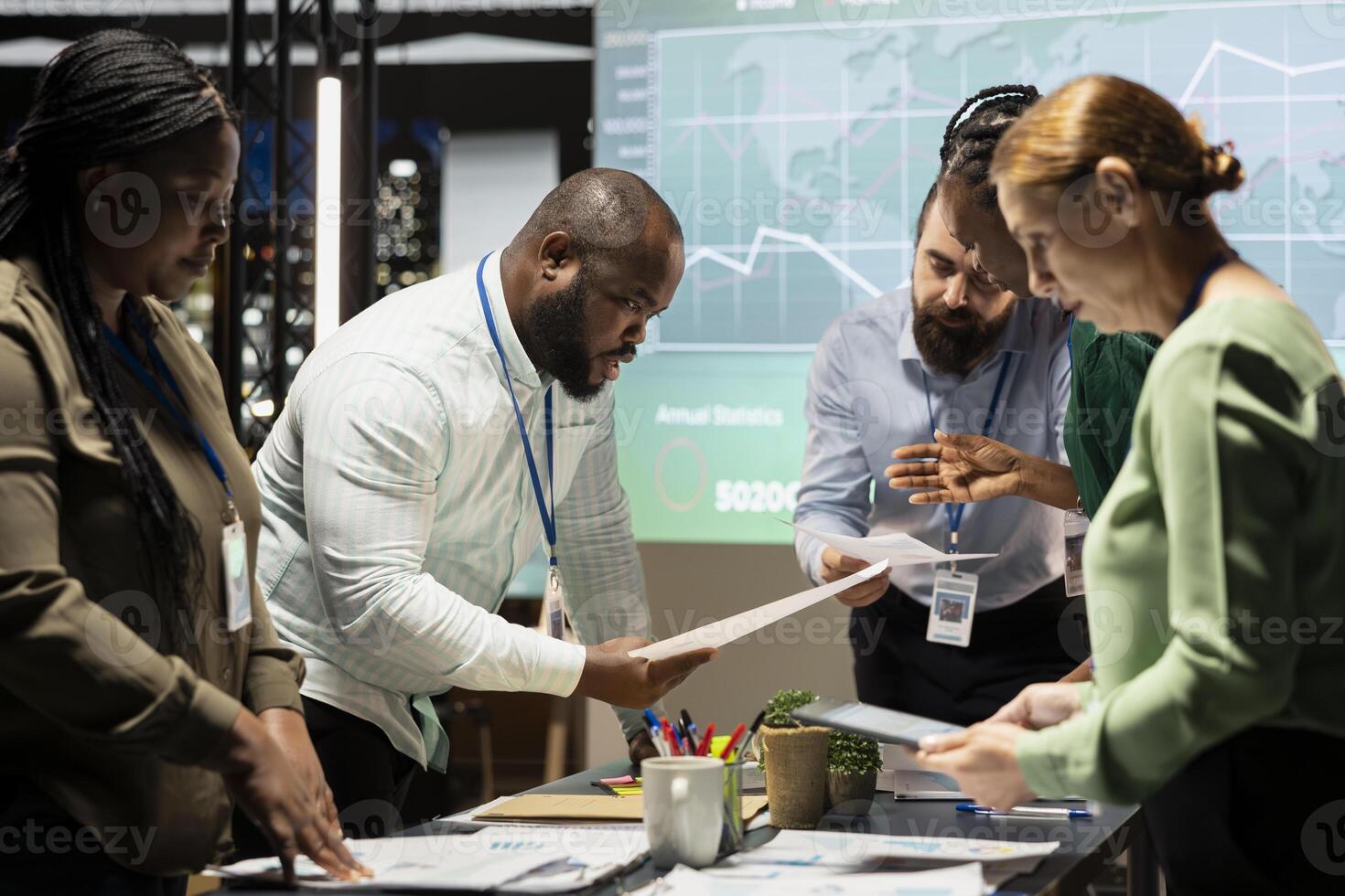 Diverse project team meeting after hours to share data visualization reports, discuss business intel and prepare forecasts for upcoming presentations to enterprise shareholders after hours. photo