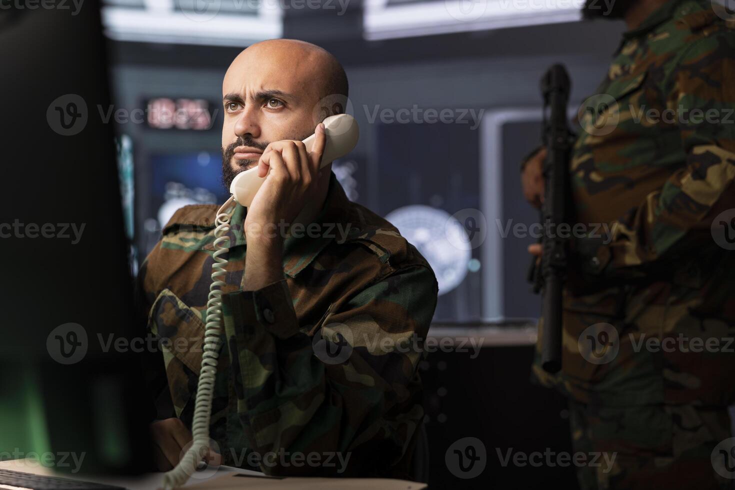 Military expert in telephone call offering information to commanders fighting on front lines. Army professional providing intel for troops in base of operations using phone photo