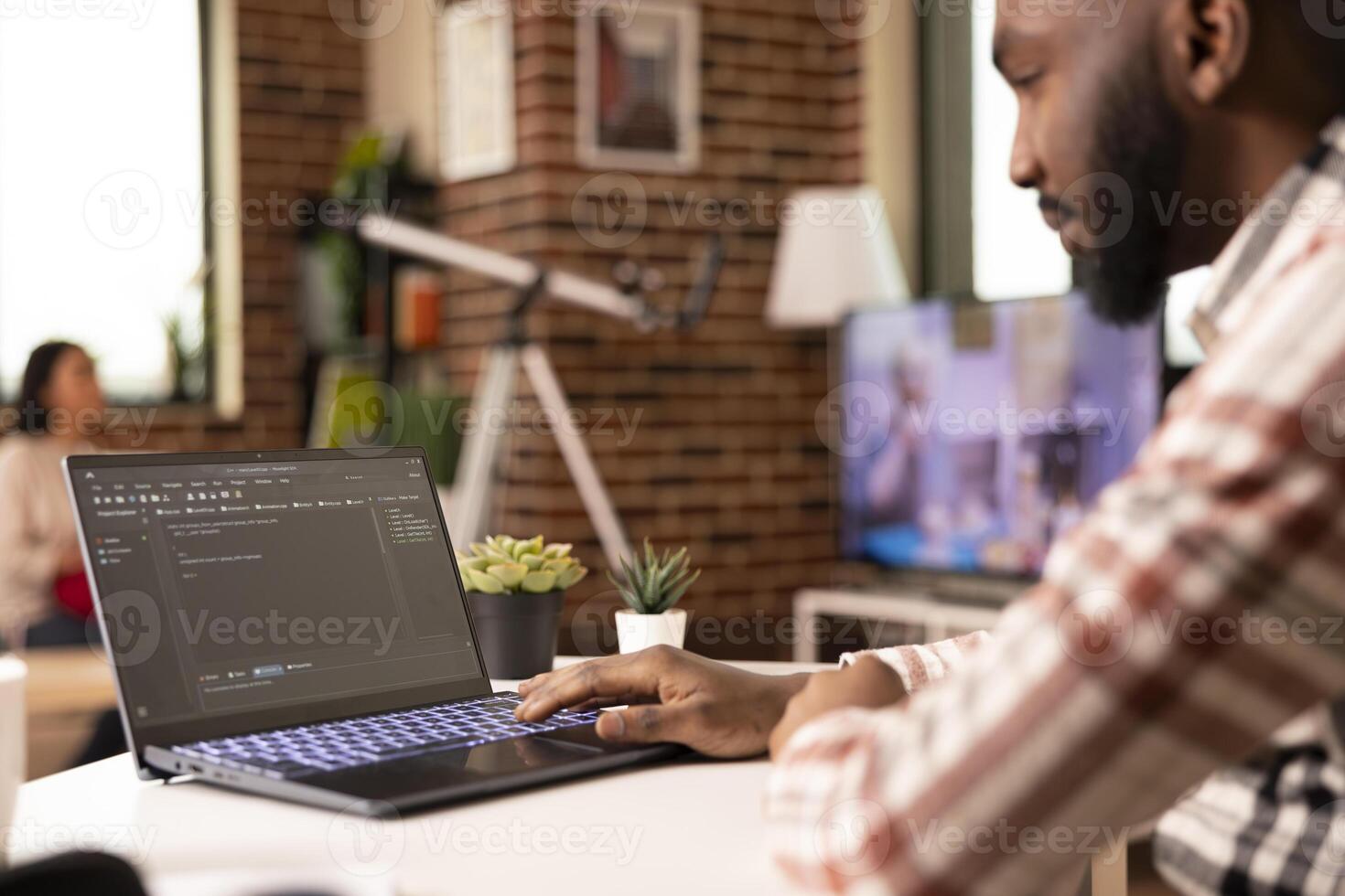 Closeup of black man typing HTML code on laptop keyboard, working remotely from desk. African american developer writing website code and running software scripts for tech company project at home. photo