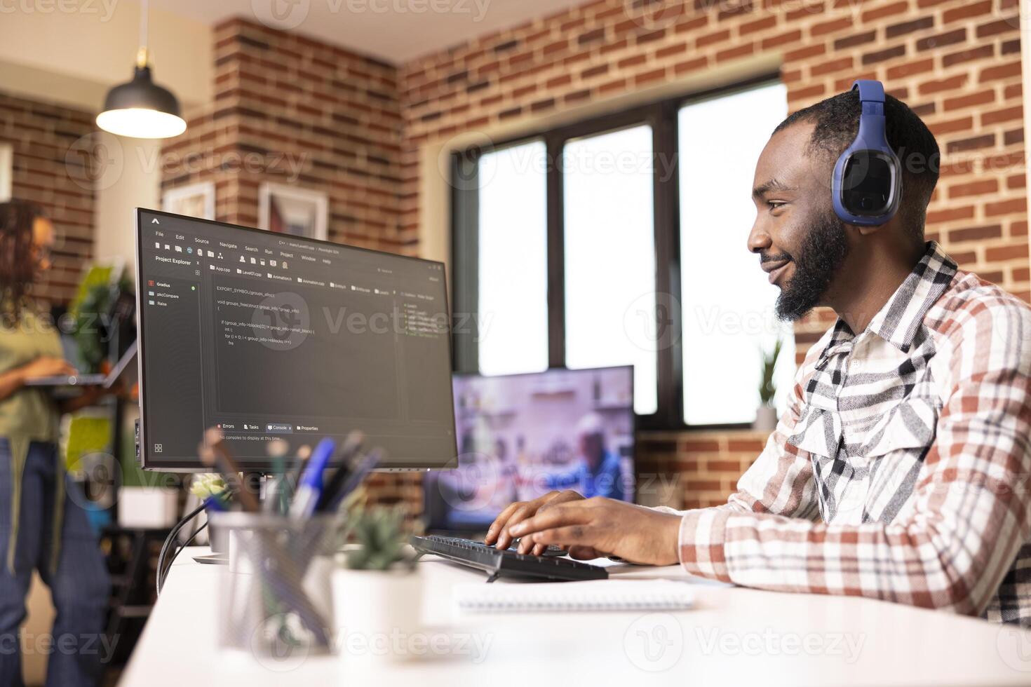 Black male programmer smiling at desktop monitor and reviewing software code. Confident developer working remotely on secure website for startup tech company from home office. photo