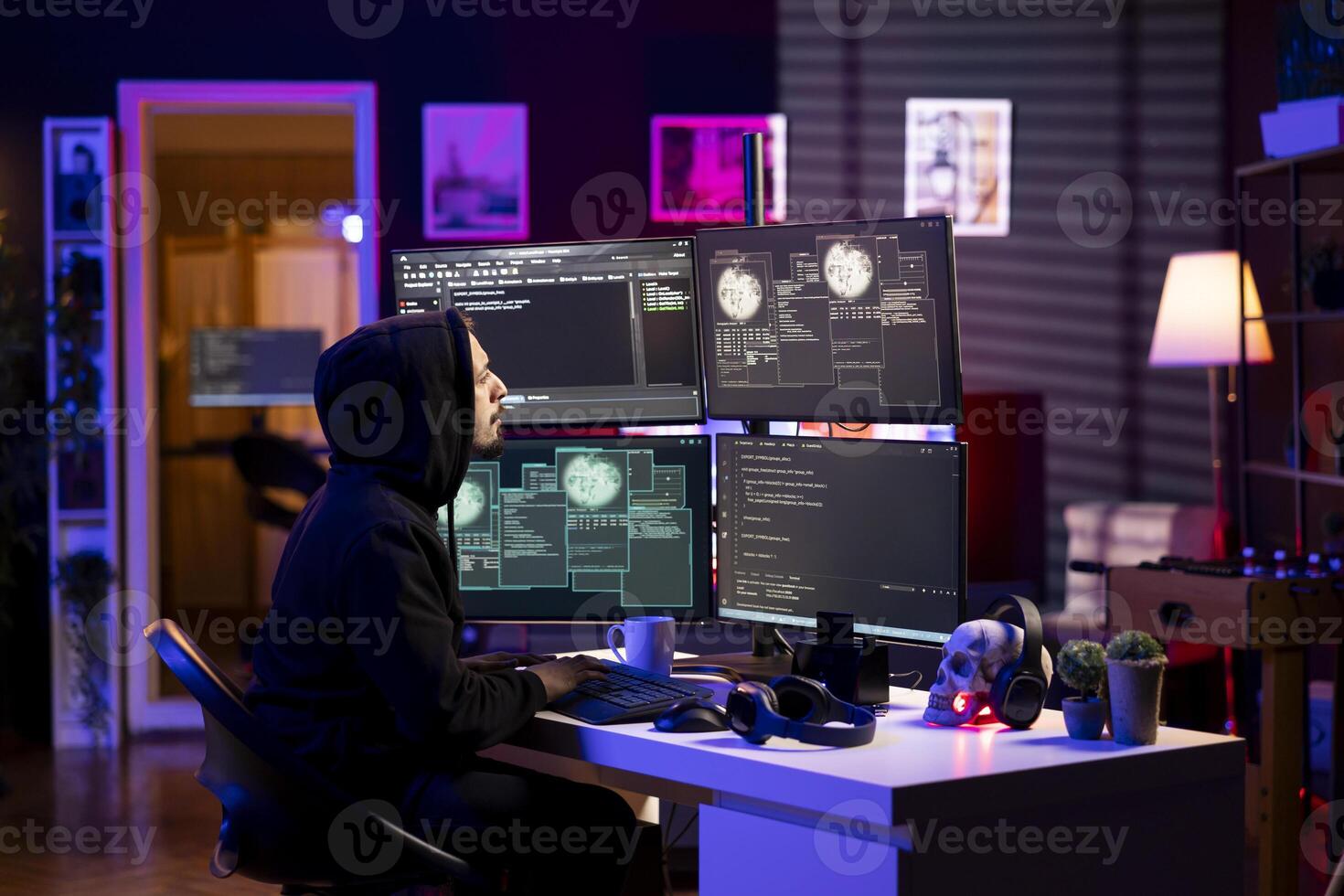 Hooded hacker in neon lit lair using PC to gain unauthorized network access, targeting unpatched connections. Rogue engineer at home bypassing security and exploit servers for stolen data profit photo